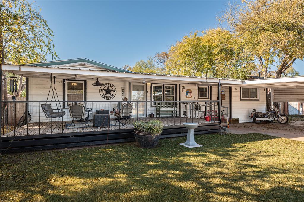 Rear view of house featuring a lawn and a wooden deck