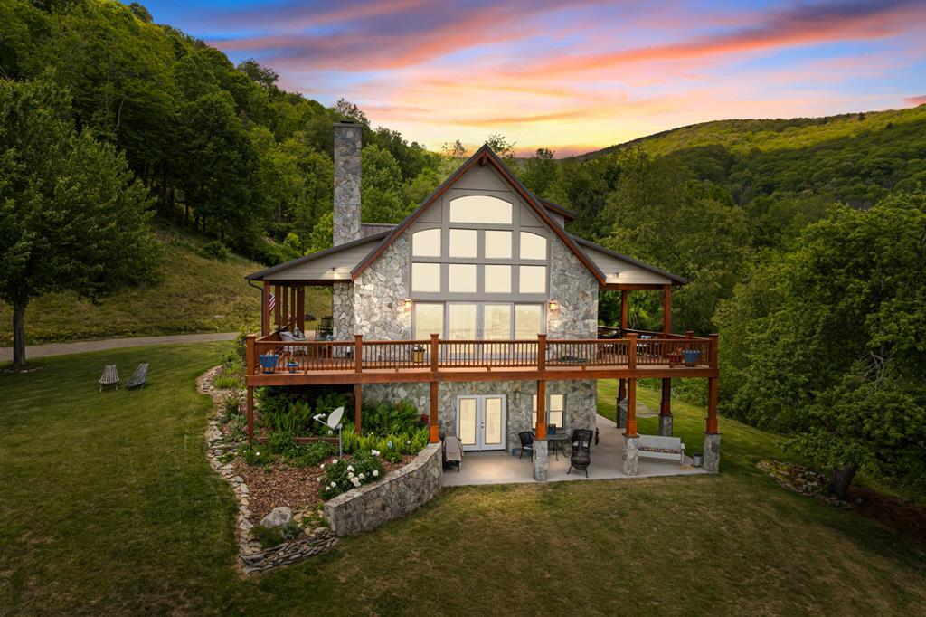 Luxury Mountain Craftsman Retreat with Panoramic Blue Ridge Views. Tucked away from the main road in the prestigious gated Point Lookout Mountain community, this exceptional custom luxury  mountain home offers total privacy at the residence and unforgettable, year-round views of the Blue Ridge Mountains. Perched at approximately 3,500 feet on 5.475 private acres, the 4-bedroom, 3.5-bath home provides more than 3,000 square feet of thoughtfully designed living space in one of Grayson County's most spectacular mountain settings. Blending Mountain Craftsman architecture with the warmth of a luxury lodge and the clean lines of a contemporary mountain retreat, the home features exposed timber posts, an impressive stone chimney, a metal roof, and expansive wraparound decking. Oversized covered porches and the home's natural materials allow it to blend beautifully into the surrounding landscape. The centerpiece is the dramatic floor-to-ceiling window wall and large glass gable overlooking the mountains. Natural light fills the interior while panoramic views create an ever-changing backdrop of brilliant sunrises, colorful sunsets, rolling clouds, seasonal foliage, and distant ridgelines. Whether relaxing beside the fireplace, enjoying coffee on the deck, or gathering around the outdoor firepit beneath the stars, the view remains the defining feature of this remarkable property. Built for comfort, quality, and efficiency, the lower and main levels feature 12-inch insulated concrete walls. High-quality Pella windows and doors are engineered for high-wind performance, while the durable metal roof provides lasting peace of mind. Hardwood flooring extends throughout the main and upper levels, with custom tile in the bathrooms and utility room. Two fireplaces—one wood-burning and one with gas logs—add warmth and character, while a heat pump and propane backup heat provide year-round comfort.The spacious floor plan is ideal for entertaining and hosting guests.