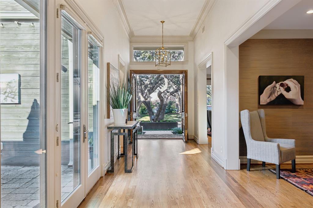 Entryway featuring crown molding, wood finished floors, a chandelier, and a towering ceiling
