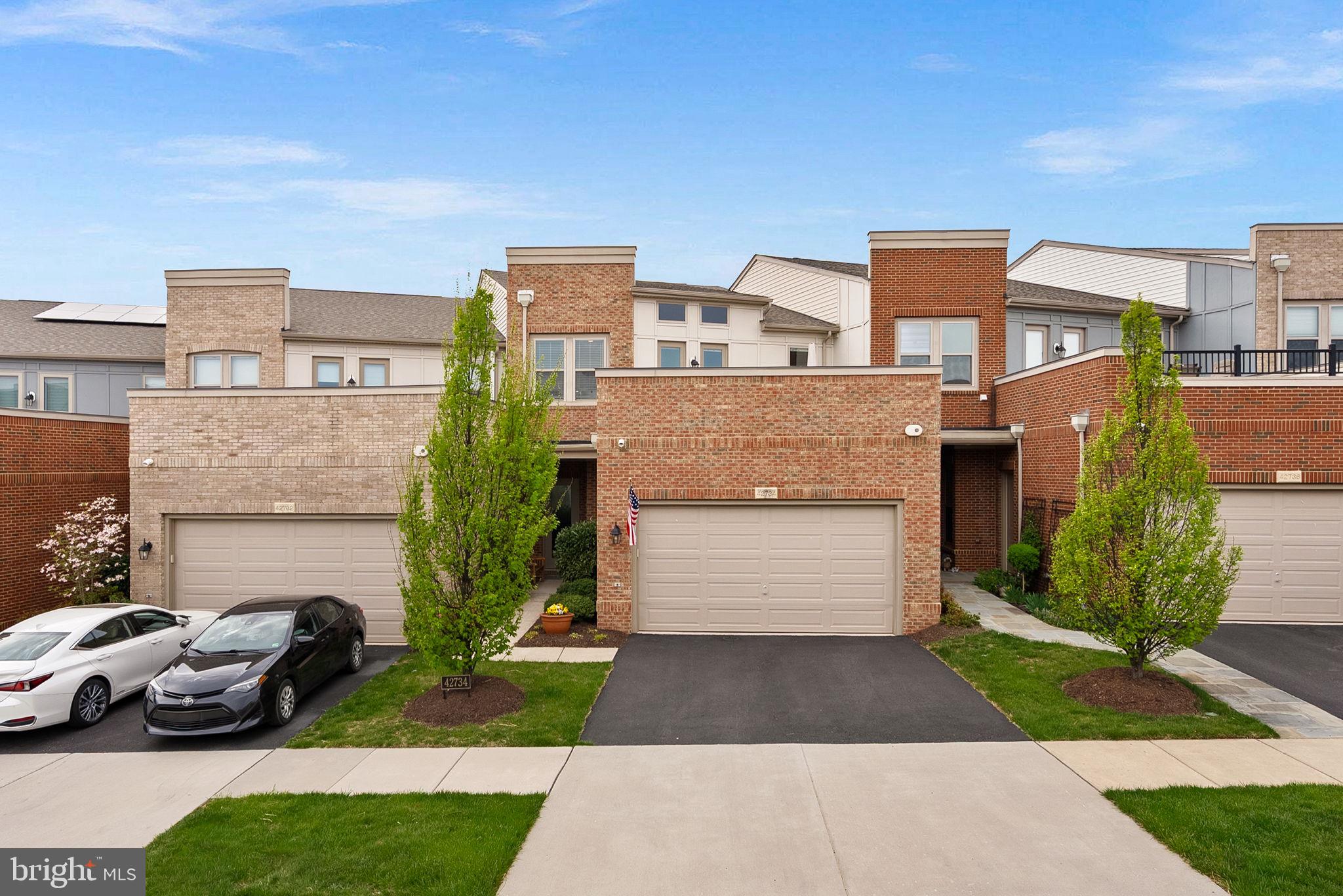 Welcome to the highly sought-after 55+ community of Birchwood at Brambleton, where lifestyle and comfort come together seamlessly. This barely lived-in townhome offers 4 bedrooms and 3.5 baths, thoughtfully designed to accommodate a variety of living arrangements with dual primary suites on both the main and upper levels.A neutral palette throughout creates the perfect blank canvas, ready for your personal touch, while custom built-in bookshelves add both character and functional design. The main level features gleaming hardwood floors and a beautifully appointed kitchen with granite countertops, stainless steel appliances, and effortless flow into the living and dining spaces—ideal for everyday living and entertaining.Outdoor living is exceptional and truly sets this home apart. Enjoy a custom deck with a built-in drainage system, a patio just off the kitchen for easy indoor-outdoor gatherings, and a rooftop terrace showcasing peaceful water views—perfect for relaxing or entertaining guests.Privately positioned with a rare treed buffer and no homes directly behind, this home offers a level of privacy not often found in townhome living.Birchwood at Brambleton is known for its resort-style amenities centered around a stunning 20,000 sq. ft. clubhouse featuring indoor and outdoor pools, a fitness and wellness center, yoga studio, golf simulator, art studio, theater and game rooms, and indoor/outdoor social spaces. Residents also enjoy pickleball and bocce courts, scenic walking and biking trails, community gardens, a fishing pier, and a full calendar of social events and activities designed for an active adult lifestyle.This is a rare opportunity to enjoy low-maintenance living in one of Loudoun County’s premier active adult communities.