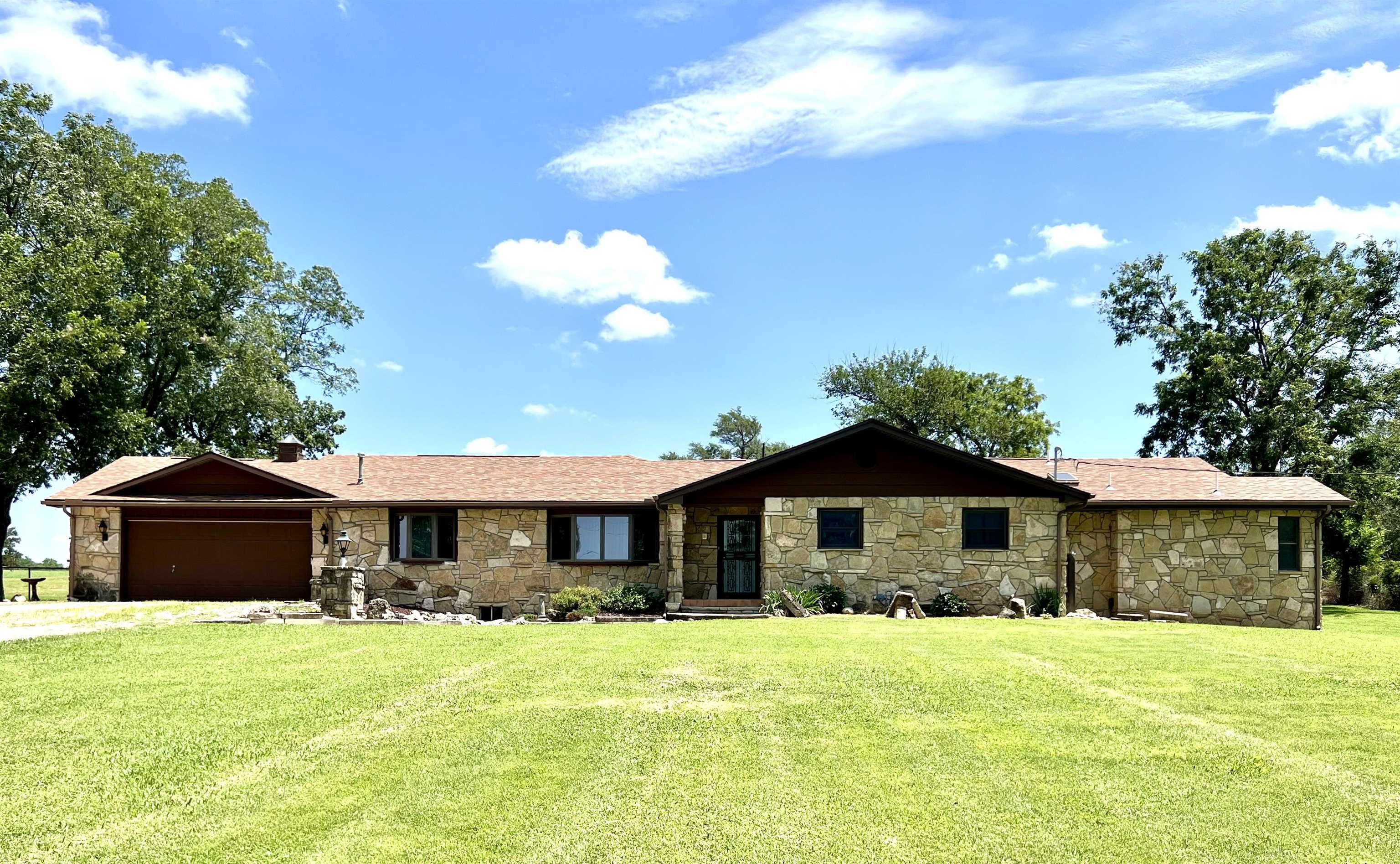 New Listing!!! – Country Living Just Minutes from Town! Enjoy the perfect blend of peaceful country life and convenience with this spacious property just five minutes downtown Arkansas City. Nestled on 9.8 prime acres, this beautiful stone ranch-style home boasts over 3,000 sq ft of main-level living space—plenty of room to stretch out and enjoy. Step inside to an enormous living and dining area, with working gas fireplace.  Perfect for entertaining or relaxing with family. The open kitchen is a chef’s dream, featuring concrete countertops, wood cabinetry, and rustic vinyl flooring that ties the space together with warm country modern feel. You’ll fall in love with the master suite, complete with a luxurious bath that includes a garden tub, large walk-in shower, and double sinks. Two additional bedrooms are conveniently located near a full bath, plus there’s a third full bathroom with another walk-in shower. The huge family room addition offers ample space for multiple seating areas, room for your BIG SCREEN movie night , or anything your lifestyle demands. Step out back (on the east side of the home) and you’ll find a cement patio perfect for morning coffee or evening relaxation. Outbuildings include: A 36’x29’ Morton building shop, small shed ideal for your riding mower, and chicken coop.  Also a pole barn ready for your outdoor farm equipment.  This is your chance to own a beautifully updated home with over 8 acreage of native grass, room to roam, and plenty of space for hobbies, animals, or just enjoying the great outdoors. DON'T DELAY CALL TODAY!!!!