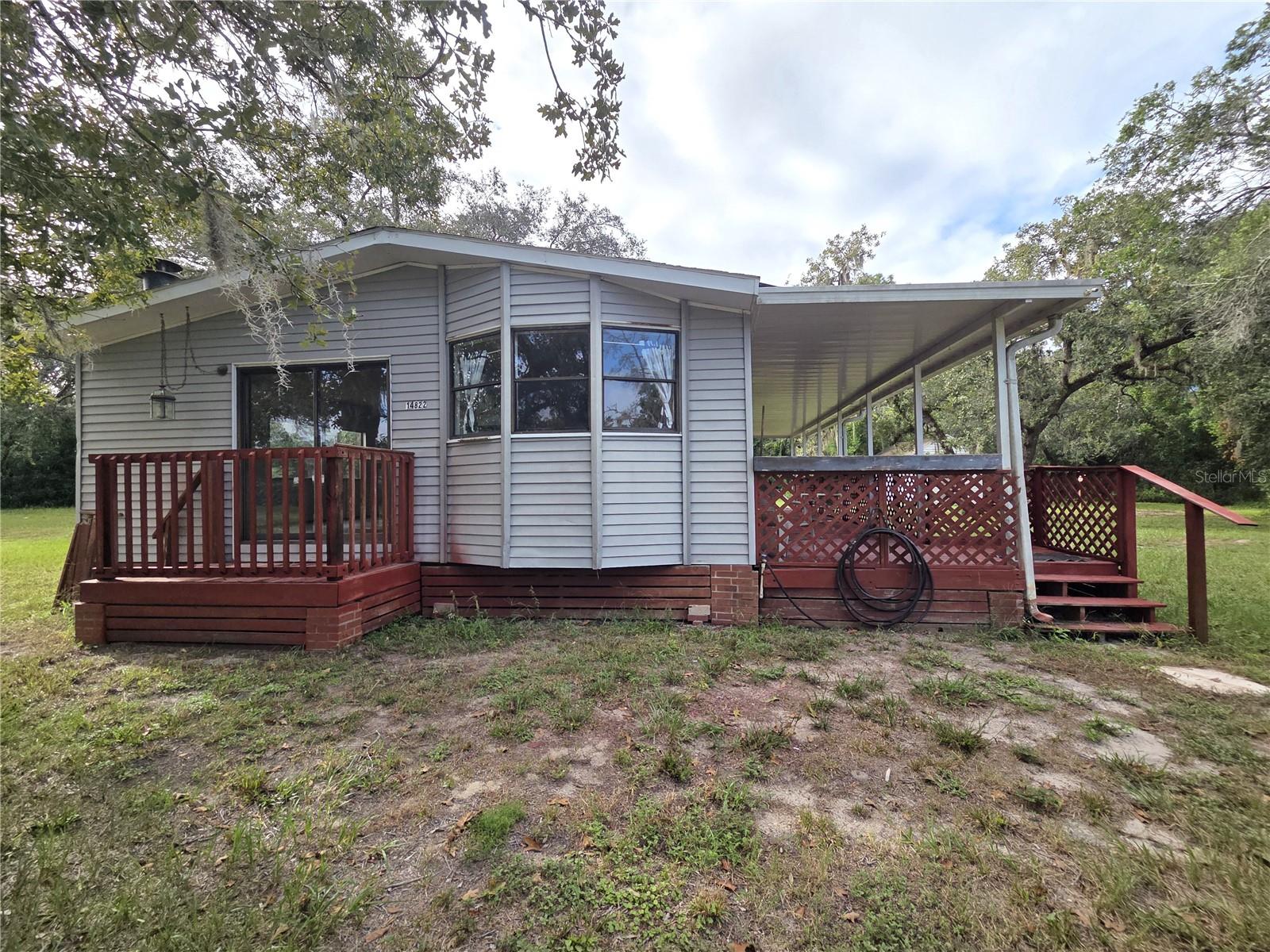 Spacious 2 bedroom, 2 bath manufactured home on 1.55 acres zoned AR. This property features an open floor plan with new luxury vinyl flooring, a huge covered porch, an indoor laundry room, and a roof replaced just 4 years ago on both the home and the garage. The primary bedroom offers its own en-suite bathroom, and both bedrooms include walk-in closets for plenty of storage. The kitchen has a breakfast bar and opens to the dining room, which features built-in storage and sliding glass doors that lead to the porch, while the living room boasts a cozy fireplace and sliding glass doors that open to the side entrance. The oversized 2-car garage includes loft storage, additional storage space, and a first-level apartment with its own covered entry, perfect for guests, rental income, or an in-law suite. The yard is fully fenced with a gated entry and also includes a shed for even more storage. Bring your boats, RVs, and toys—there is more than enough space to make this property your own. This one-of-a-kind property offers flexibility and a great opportunity to enjoy Florida living. Property is located approximately 3 miles to the Suncoast Highway, 8 miles to boat ramp, 3 miles to shopping, restaurants, and hospital.