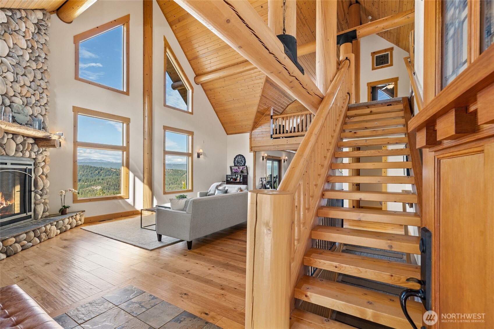 Open staircase and substantial log construction showcase the craftsmanship and architectural character found throughout the home.