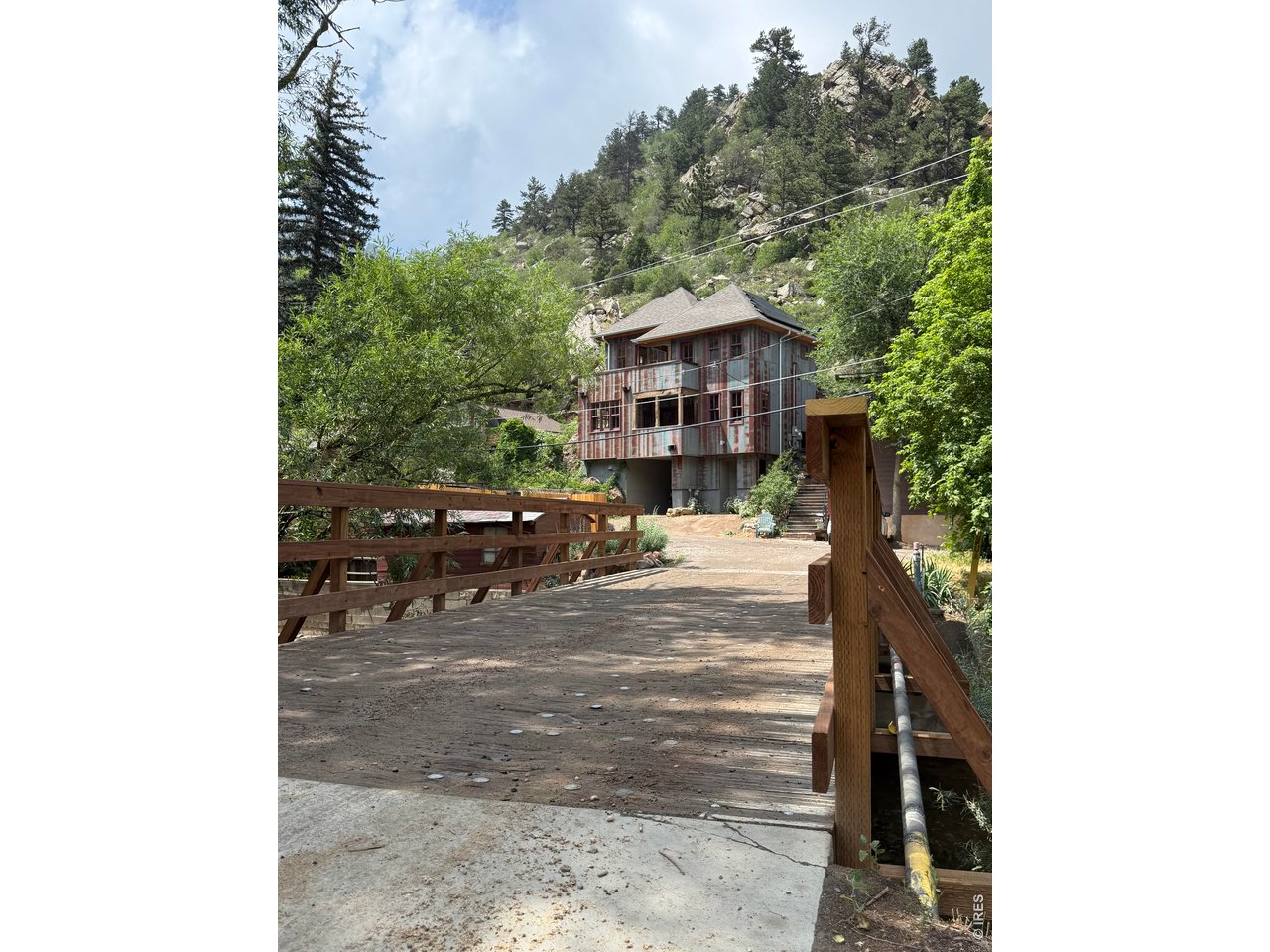 NEW PRICE! Designed and built by world-renowned rock climber Christian Griffith, this custom residence in Eldorado Springs is among the most architecturally compelling homes on the Front Range. Reclaimed 1850s barn roofing forms the distinctive metal siding, evoking the spirit of a historic miner's cabin. Antique red oak plank floors with radiant heat sprawl throughout an open layout showcasing views from every window. Carrara marble countertops, a live-edge red oak slab bar and high-end appliances define a kitchen of rare artistry. A one-of-a-kind winder staircase with treads crafted from red oak planks interwoven with willow branches ascends to south-facing balconies on both levels. A three-fold accordion door dissolves the boundary between indoors and the surrounding canyon landscape. The home is built directly into the bedrock, with a subterranean rear that naturally regulates temperature, a below-grade wine cellar and HRV fresh-air system. South Boulder Creek flows at the doorstep, and Eldorado Canyon State Park is moments away. House is tapped with pure Eldorado Spring water!
