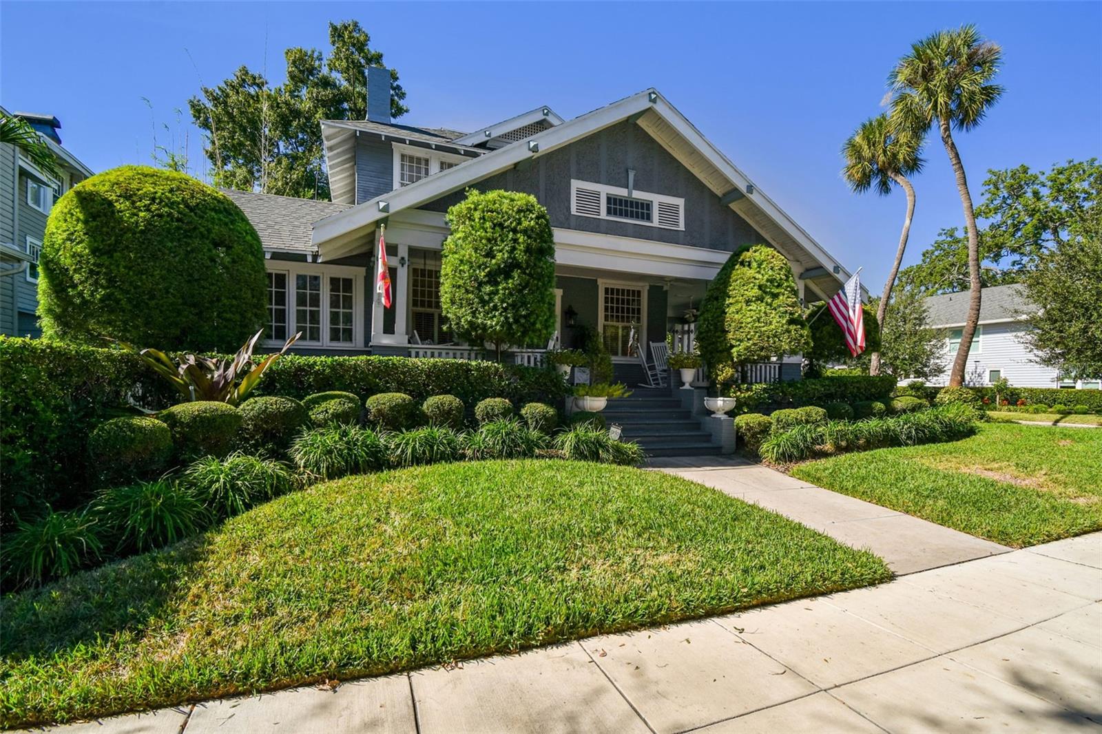 Set on a prominent corner lot in the heart of Hyde Park, this historic home offers timeless character, thoughtful updates, and arguably some of the best views of Bayshore Boulevard and six blocks from Hyde Park Village. A sweeping wrap-around porch immediately welcomes you, anchored by a charming Dutch door that serves as a nod to the home’s rich history and sets the tone for what lies within. Step inside to find soaring 11-foot ceilings and a formal living room centered around a wood-burning fireplace with coffered ceilings and raised paneled wainscoting creating a warm and inviting first impression. Just off the living room, a sun-filled sitting room provides a peaceful retreat bathed in natural light—ideal for reading, relaxing, or enjoying morning coffee. You are welcomed through the dining room that overlooks the side patio and garden through large original windows.The home then opens beautifully into the kitchen and main living area, where an open-concept layout allows for effortless flow and everyday living. The kitchen features two islands, gas stove, bar seating, custom cabinetry, and a built in work station. An eat-in breakfast area connects seamlessly to the large living space and kitchen, making it perfect for entertaining. Two separate porches extend from both the living area and the breakfast space, offering multiple opportunities to enjoy the lush grounds and meticulously landscaped outdoors.The primary suite is conveniently located on the main level and serves as a private sanctuary. The updated en-suite bathroom includes a soaking tub, walk-in shower, and custom inset storage thoughtfully designed to fit the space. Off the primary bedroom, a sunroom offers exceptional flexibility—ideal for a home office, nursery, gym, expanded closet, or private TV or reading room. An updated half bath with a designer’s touch completes the main floor. Upstairs, the second level features four bedrooms, including two generously sized rooms with peek-a-boo water views of Bayshore Blvd. Two additional bedrooms are filled with historic charm and character, complemented by two full bathrooms that serve the upper level with ease. Adding to the property’s versatility is a detached guest house located above the one car garage, complete with a full bathroom. Perfect for visitors or a private workspace, this additional living space enhances both functionality and value. Additional features include 4 AC units (2017-2026) with all new duct work, 3 water heaters (2020-2024), structural support updated (2025), and all electrical wiring updated (2025). This exceptional Hyde Park residence seamlessly blends historic charm, thoughtful design, and modern livability—all in one of Tampa’s most iconic locations.