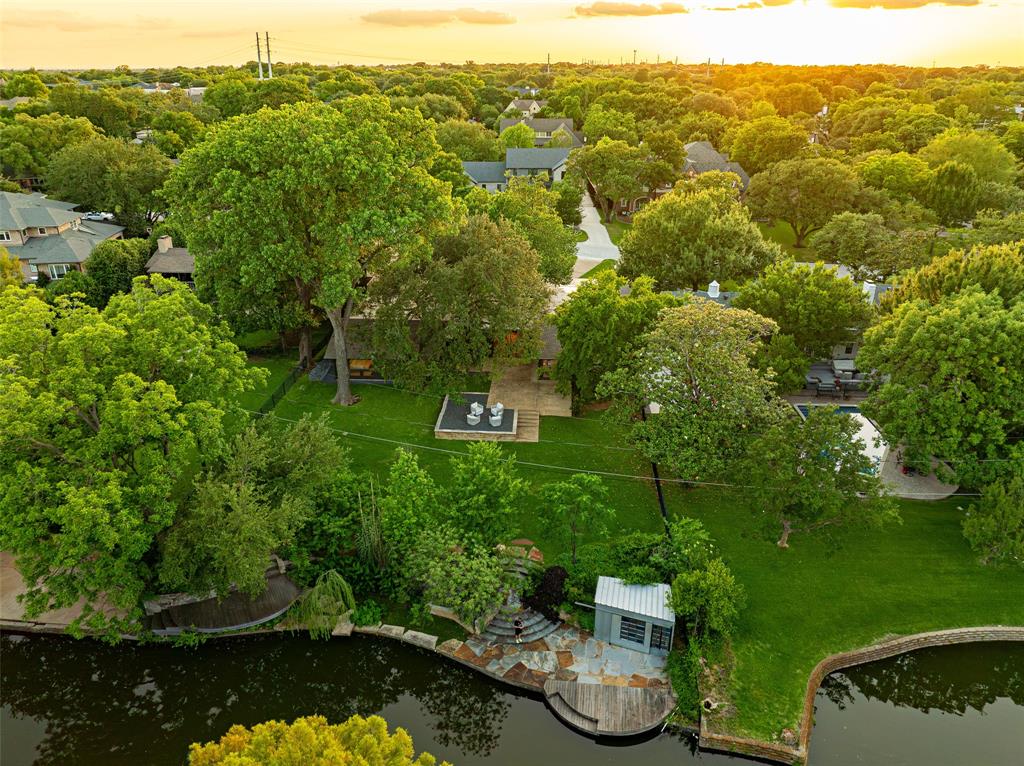 A One of One! Rarity in Preston Hollow. This Re-imagined Mid Century Modern from the 1950s sits upon a private Oversized Lake Lot with a Boat House. You feel like you are on vacation the second you step through the doors. The restoration on this home began in 2025 with designer Debra Stewart and prior installment by Charles D Bobo. The Design improved the functionality of the home while maintaining the homes architectural spirit. In the Kitchen new Clean lined white oak cabinetry was installed, Rare turquoise-toned imported granite counters, New SS Appliances, water filler, backsplash, under-mount lighting and refinished oak floors. Living spaces were opened creating a more expansive and connected environment. A new fireplace clad in Old Chicago Brick flanked by Built in Oak cabinets. Near the entry a custom architectural slat wall feature offers subtle separation while adding rhythm and texture to the interior. Throughout the home electrical systems were modernized, insulation was upgraded with foam insulation, and New Hvac was installed. Primary Bedroom was fully updated to match the quality of the main living spaces w New Hardwood Floors, cabinets, counters, lighting, and plumbing. The front of the home has a separate space for an office or gym with an ensuite full bath. Outside was improved with fresh paint, drainage, and landscaping.  While the lakeside fishing hut offers a charming retreat for casting a line into the fully stocked lake. A garden sink and outdoor shower adds to the properties unique character.  Set within a tranquil lakeside setting. This home offers a rare blend of architectural authenticity and modern livability. From its natural materials to the thoughtful updates, Westmere Circle is a home that respects the past while beautifully embracing the present.