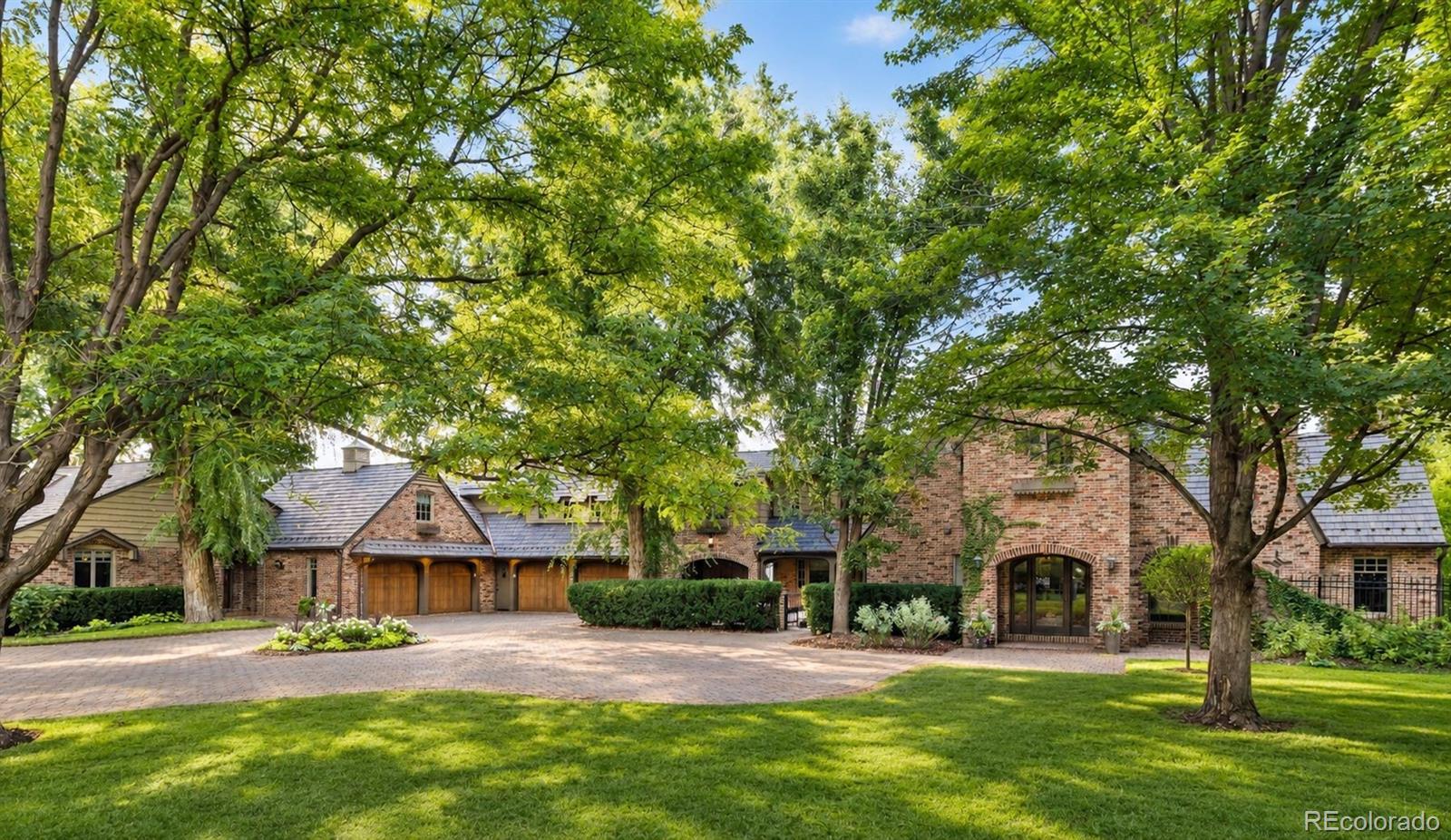 Rarely does a property of this scale and privacy become available in the heart of Old Cherry Hills. Set on more than three gated acres in one of Denver’s most coveted neighborhoods, this extraordinary estate is concealed behind a veil of mature trees. Extensively renovated over the past several years, the property brings together an English country-inspired main residence, attached two-bedroom guest house, detached entertaining pavilion, pool, spa, and remarkable grounds. Inside, timeless character meets elevated modern design. The kitchen is a striking centerpiece with Odyssey dolomite waterfall islands, Aspen Leaf cabinetry, a hand-blown John Pomp fixture, and a generous walk-in pantry. The living room centers on a cast-stone fireplace, while the sunroom opens through accordion doors to the gardens, terraces, and reflection pond. In the distinctive dining room, hand-carved paneling and built-ins from a 15th-century English church create a dramatic juxtaposition against refined modern finishes. The primary suite is a private retreat with balcony, fireside sitting room, dual walk-in closets, and beautifully appointed dual baths featuring marble, terrazzo, and Waterworks fixtures. An approximately 2,000-bottle wine cellar provides another memorable space. Connected to the main residence, the guest house offers its own kitchen, living and dining areas, laundry, and two en-suite bedrooms. Beside the pool, the detached entertaining pavilion is a destination of its own, featuring a living area and bar, plus a concealed retreat with golf simulator and media space. A pool and spa, sport court, koi pond, rose garden, fire pit, terraces, and original barn unfold across the secluded grounds. Four garage spaces, Lutron controls, automated shades, and whole-home water filtration add modern ease. With more than three private acres and a collection of spaces unlike anything else in Cherry Hills Village, this remarkable estate stands as a true crown jewel of Old Cherry Hills.