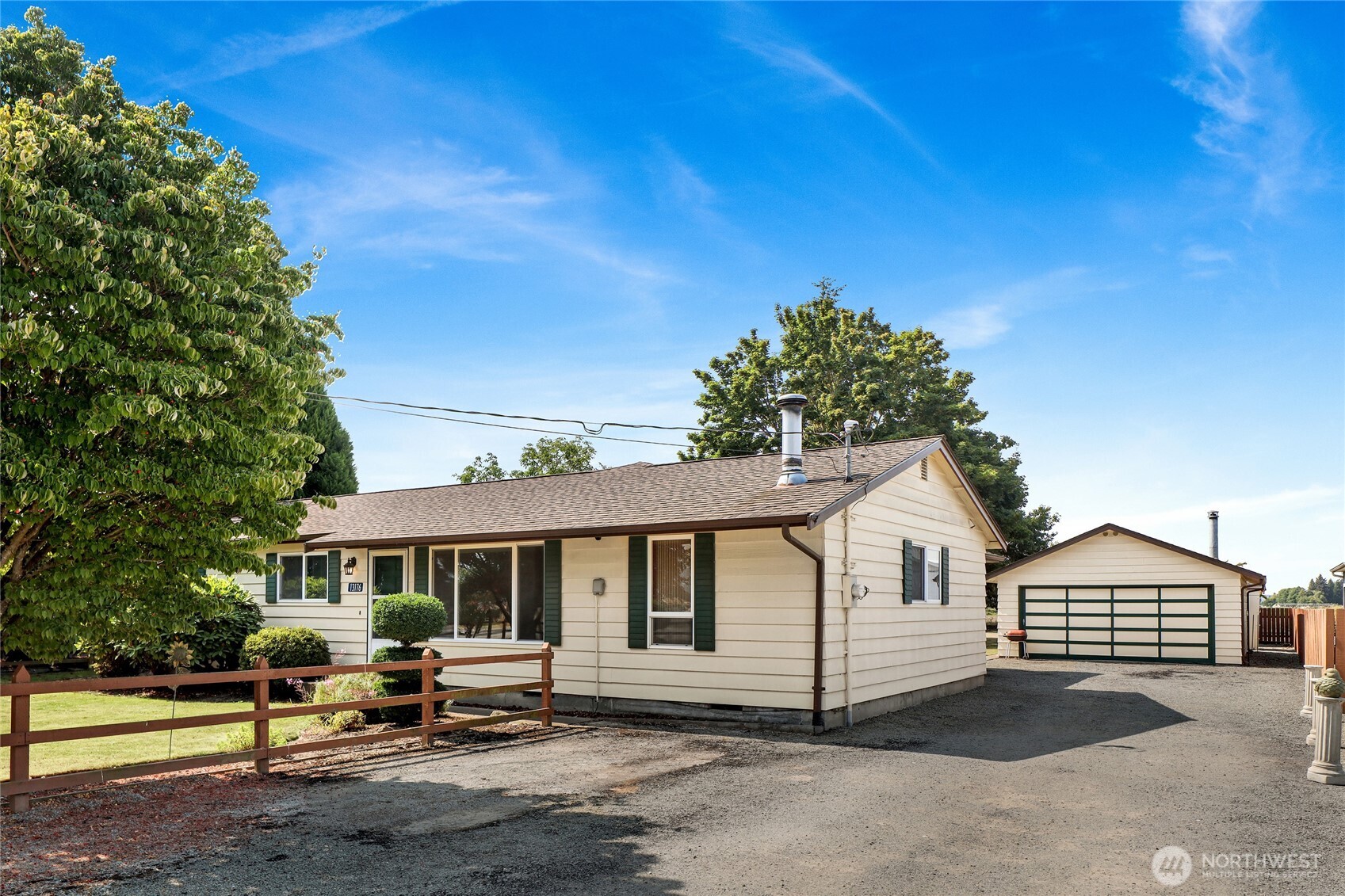 Welcome home to your own peaceful rural retreat! This charming single story ranch-style home combines comfortable everyday living with incredible versatility on a shy half acre of flat land. The functional layout features an inviting living room, a large family room anchored by a cozy wood stove, a bright kitchen with plenty of cabinetry & ample counter space, and a dedicated utility room with convenient overhead storage. You will also find three generous bedrooms and a full bathroom down a private hallway as well as a 3/4 bath conveniently located by the back door. Outside, the covered back porch invites you to kick back, relax, and take in the beautiful lawn and surrounding mature trees. The large detached workshop—complete with built-in cabinetry, a deep garage bay, and a cozy free-standing stove—offers the perfect haven for hobbyists, trade projects, or extra storage. The main highlight here though is the enormous back yard which offers an incredible opportunity for entertaining large gatherings, growing an amazing private garden, or practicing your favorite outdoor hobby! It’s a truly wonderful place to relax, create, and feel at home.