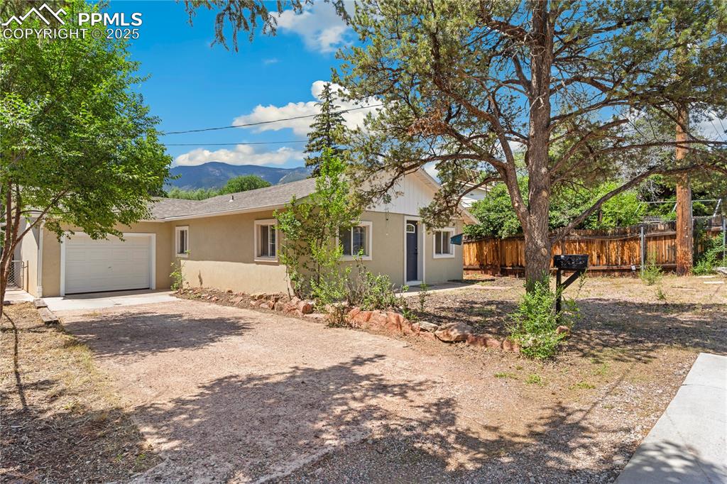 Charming Manitou Springs Gem Near Garden of the Gods! Nestled in the heart of Historic Manitou Springs, this inviting single-level home offers timeless character, thoughtful updates, and an unbeatable location—just a short walk to Garden of the Gods and Fields Park! Step inside to find wall-to-wall real hardwood floors, rich wood wall paneling, and abundant natural light that preserves the home’s historic charm while blending beautifully with modern updates. The spacious living room flows effortlessly into the dining area and kitchen, creating a warm and open layout perfect for entertaining or relaxing. The kitchen is a standout with slab granite countertops, stainless steel appliances, modern shaker-style cabinets, an under-mounted sink, and a stylish arched faucet with a pull-down sprayer. Enjoy casual meals at the breakfast bar, or host guests in the adjacent dining area. All three bedrooms feature hardwood floors, while the full bathroom has been tastefully updated with ceramic tile flooring, a sleek vanity, a contemporary circular mirror, and subway-tiled shower walls that extend to the ceiling for a polished look. Outside, the fully fenced backyard offers privacy, mature trees, and a covered patio ideal for outdoor dining or morning coffee. Additional features include newer vinyl windows, recessed lighting, a one-car attached garage, and a long driveway for extra parking. Just steps from Fields Park—featuring pickleball courts, disc golf, a skate & bike park, and a scenic riverside path—you’ll enjoy an active lifestyle with nature and recreation at your doorstep. Don’t miss this rare opportunity to own a piece of Manitou Springs history with all the modern comforts!