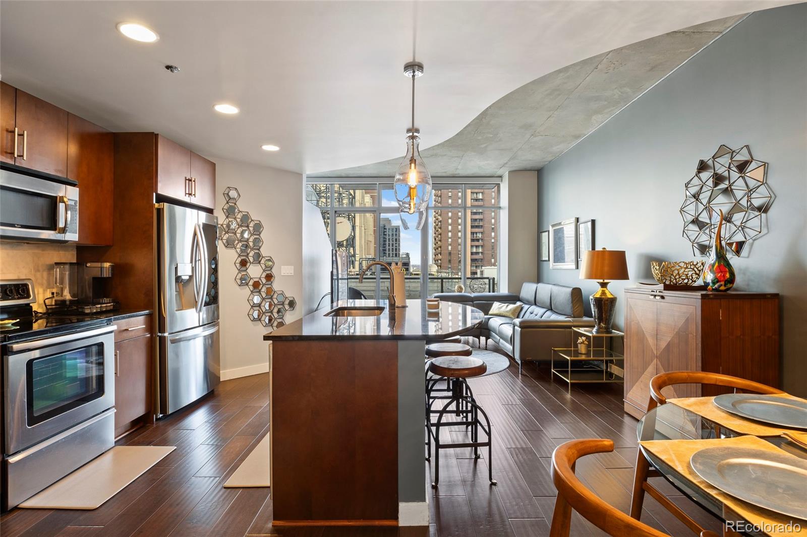 Discover modern downtown living in this exquisitely upgraded one-bedroom plus den residence at SPIRE.  Thoughtfully designed with attention to every detail, this home showcases custom paint, real walnut-stained hardwood floors throughout, granite countertops, a custom Carrara marble backsplash, designer lighting, and motorized blinds. Floor-to-ceiling windows frame breathtaking city and mountain views, filling the home with natural light. Recent updates include a new LG refrigerator, Bosch dishwasher, Electrolux washer and dryer, and a newly installed bath fixture. The bedroom features a generous closet and a beautifully finished bath with designer finishes, while the spacious den provides flexible use as a home office, guest area that fits a queen bed, or a creative studio. Well maintained and move-in ready, this chic residence is located in one of Denver’s premier high-rise communities. SPIRE offers a 24-hour front desk, year-round fitness center, heated rooftop pool and hot tub, multiple lounges, a theater, and unmatched proximity to the DCPA, dining, shopping, and light rail. Most furnishings are available for purchase—please inquire for pricing. And, with a deeded parking space and oversized storage, this residence truly offers it all.