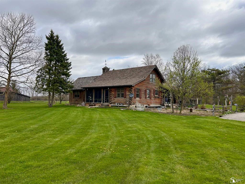 Tucked away on 5 partially wooded acres, this one-of-a-kind log home offers the perfect blend of privacy, character, and functionality. Surrounded by mature trees and perennial gardens, the setting feels like your own private retreat while still offering all the conveniences of modern living. Step inside and you're immediately welcomed by the warmth and charm that only a true log home can provide. The spacious living room features a vaulted ceiling and a stunning stone fireplace, creating a cozy yet impressive focal point for gatherings. Natural light pours in, highlighting the rich wood tones and rustic details throughout. The kitchen is designed for both everyday living and entertaining, complete with a center island, generous counter space, and a bright breakfast nook overlooking the property. A separate formal dining room provides the perfect setting for holidays and special occasions. The main level also includes a dedicated home office-ideal for remote work or quiet study. With 4 bedrooms and 3 full baths, there's room for everyone to spread out comfortably. The partially finished basement adds even more flexibility, featuring a bar area that's perfect for game nights, movie marathons, or hosting friends and family. Outside, the amenities truly shine. Enjoy summer days in the 24-foot above-ground pool, complete with surrounding deck and pool house for convenience. The large detached garage includes a workshop space for hobbies, storage, or projects. The impressive 28x36 pole barn with a 14x28 lean-to offers incredible versatility, and the massive loft provides even more usable space. You'll also find a charming chicken coop and playhouse, adding both function and fun to the property. A whole-house generator provides peace of mind year-round, and the newly stoned driveway offers abundant parking for guests, trailers, or recreational vehicles. The screened-in porch overlooks the front yard and is the perfect place to enjoy your morning coffee while taking in the peaceful surroundings. This property is more th