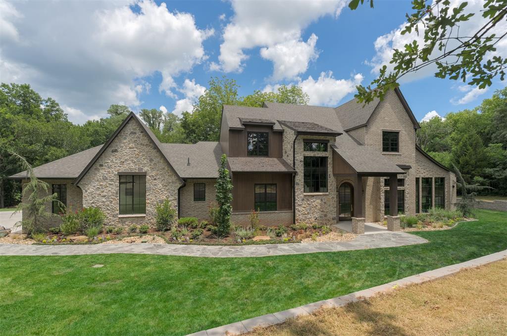 Tucked into the trees in Shoreline, this custom estate offers a rare blend of timeless design, modern livability, and natural privacy. Set on 1.6 acres in Edmond Memorial School District, the homesite is positioned off the road and surrounded by mature trees, creating a private, nature-filled setting. The property backs to wooded Corp of Engineers land near Lake Arcadia, enhancing the home’s peaceful, retreat-like feel. Thoughtfully designed for both everyday living and elevated entertaining, the home features five bedrooms—each with its own en suite bath—along with a dedicated study, sunroom, downstairs media room ideal for indoor/outdoor living, and an upstairs game room. The indoor-outdoor flow is seamless, with a backyard setting that naturally lends itself to a private, resort-style retreat. The architecture blends stone, brick, and wood-look siding with custom wood accents, striking a refined balance between classic character and fresh, transitional style. Inside, craftsmanship and intentional design selections are evident—from the statement Isokern fireplace to the richly detailed kitchen with custom millwork and a true butler’s pantry with windows that bring in soft natural light. A dedicated wine storage room adds both function and a quiet sense of luxury. Oversized wood windows frame views of the surrounding trees, creating moments that feel both grounded and serene. The sunroom, with floor-to-ceiling windows, offers a peaceful retreat tucked into the landscape, while the staircase landing features a dramatic window capturing the same tree-lined setting. The primary suite is a standout, featuring a spa-like bath with a wet room design, soaking tub, walk-in shower, and a striking corner window. Located just minutes from I-35 with convenient access to Edmond, Oklahoma City, and major medical centers—offering the ideal balance of privacy, accessibility, and lifestyle.