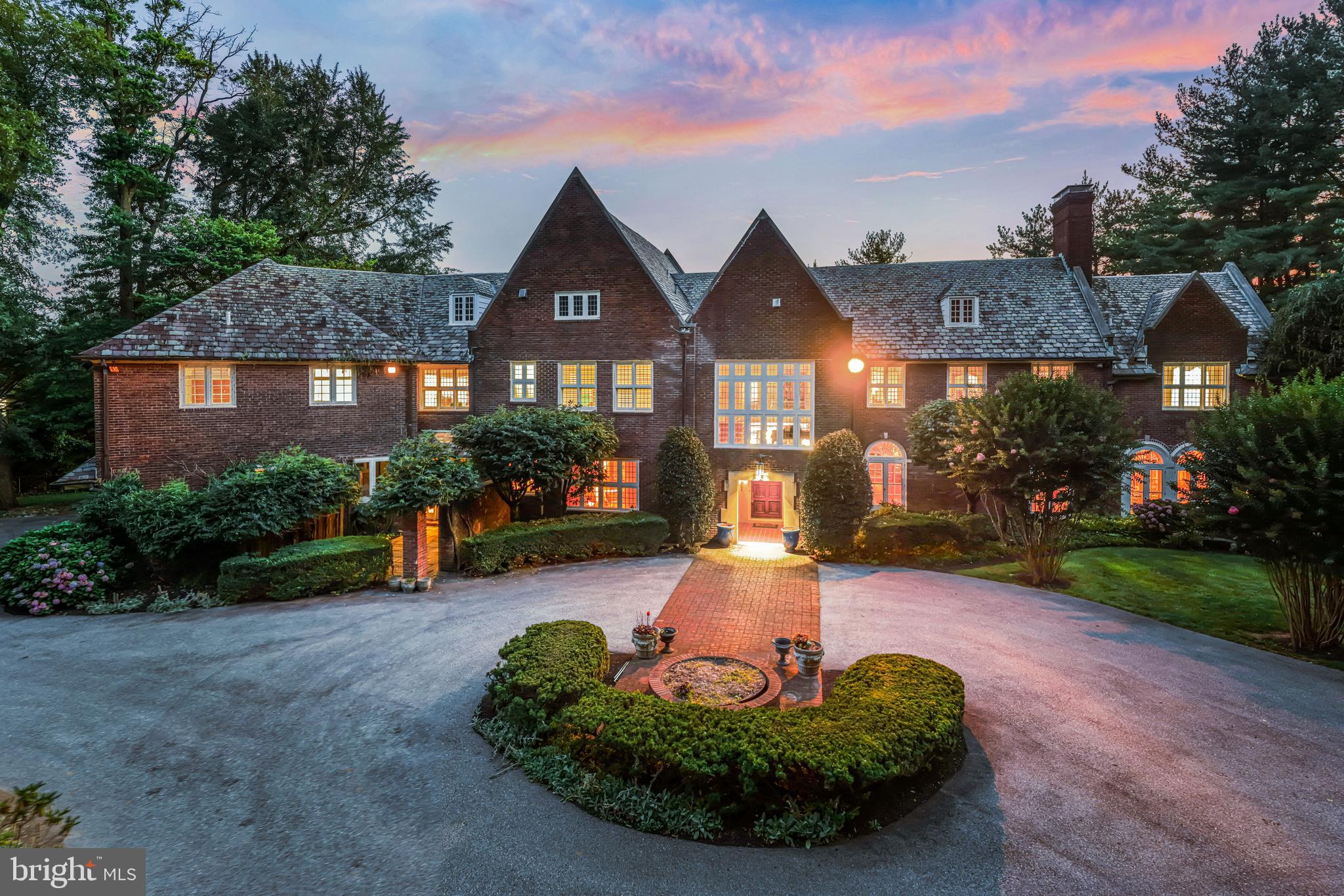 Set on 1.6 acres in sought-after Northside Villanova within Lower Merion Township, this 1924 red brick manor showcases timeless architecture with a slate roof, expansive leaded glass windows, and nearly 9,000 square feet of living space. Set back from the road, the approach is marked by a circular drive and a canopy of mature trees that frame the property with privacy.The entry vestibule opens to a dramatic foyer with wainscoting, leaded glass windows, and views through French doors to the rear terrace, flanked by the formal living and dining rooms. Natural light, hardwood floors, and detailed millwork set a welcoming tone, while a sweeping staircase with iron railings and a wood handrail rises to a landing with a built-in window seat —a  striking first impression. The generously sized formal living and dining rooms reflect the home’s distinction with high ceilings, paneled walls, and carved limestone fireplaces; six fireplaces in total. French doors continue in nearly every room, extending to large terraces on the rear of the home. The living room opens into a bright sunroom with black and white checkered tile floors, an additional fireplace, while the dining room connects to an all-season room overlooking the rear grounds. Built-in bookshelves and glass-front cabinetry enhance the architectural character of the dining room, while a butler’s pantry, a cozy sitting room with fireplace, and a formal powder room complete this wing.The kitchen features soaring ceilings, a center island, granite countertops, and generous cabinetry, some with glass-front doors, as well as professional grade appliances. A built-in banquette is framed by two-story windows that provide abundant natural light. An open rear staircase leads to a large second-floor family room that overlooks the kitchen, with built-ins and high ceilings creating a natural gathering place. Next to the kitchen, a mudroom with entry to the garage and driveway adds convenience with an informal powder room, pantry, and coat closet.At the top of the main staircase, the primary suite commands its own private wing. This large room features paneled walls, hardwood floors, a marble fireplace, and windows framing both front and rear views. A light-filled dressing room connects to the ensuite bath. In the style of homes built in this era, a second primary bath with suana is found on the opposite side of the suite. This bath also opens Jack-and-Jill style to an office (which could be bedroom 6). The configuration continues as this room connects to an additional jack and jill bathroom and an additional bedroom. Off the center hall, two additional updated bedrooms offer ensuite baths. A spacious laundry room is conveniently located nearby. Through the 2nd floor family room, is an additional sitting room and adjoining bedroom also has an ensuite bath. It could serve as an in-law or au pair suite, or a homework room. In total the home offers 5/6 Bedrooms and 6 full baths.The lower level offers a large area with daylight windows, providing potential for future finishing. This level also includes a wine cellar and additional storage spaces.The rear grounds are designed for both recreation and relaxation, featuring an expansive terrace, an inground gunite pool and pool house w/ 2 bathrooms/changing rooms, washer/dryer, kitchenette.  Also side tennis/basketball sport court. Mature trees and gardens frame the setting and provide privacy. A side entry attached garage has 2 bays.Located in the award-winning Lower Merion School District and close to many of the area’s private schools as well as renowned country clubs, the Villanova train station just one mile away, and I-476 for easy access to Philadelphia.717 N. Spring Mill Road is a distinguished Main Line estate with enduring architectural presence. While cherished by the same owners for more than 20 years, it now offers the perfect canvas for new owners to personalize, blending timeless character with modern vision.