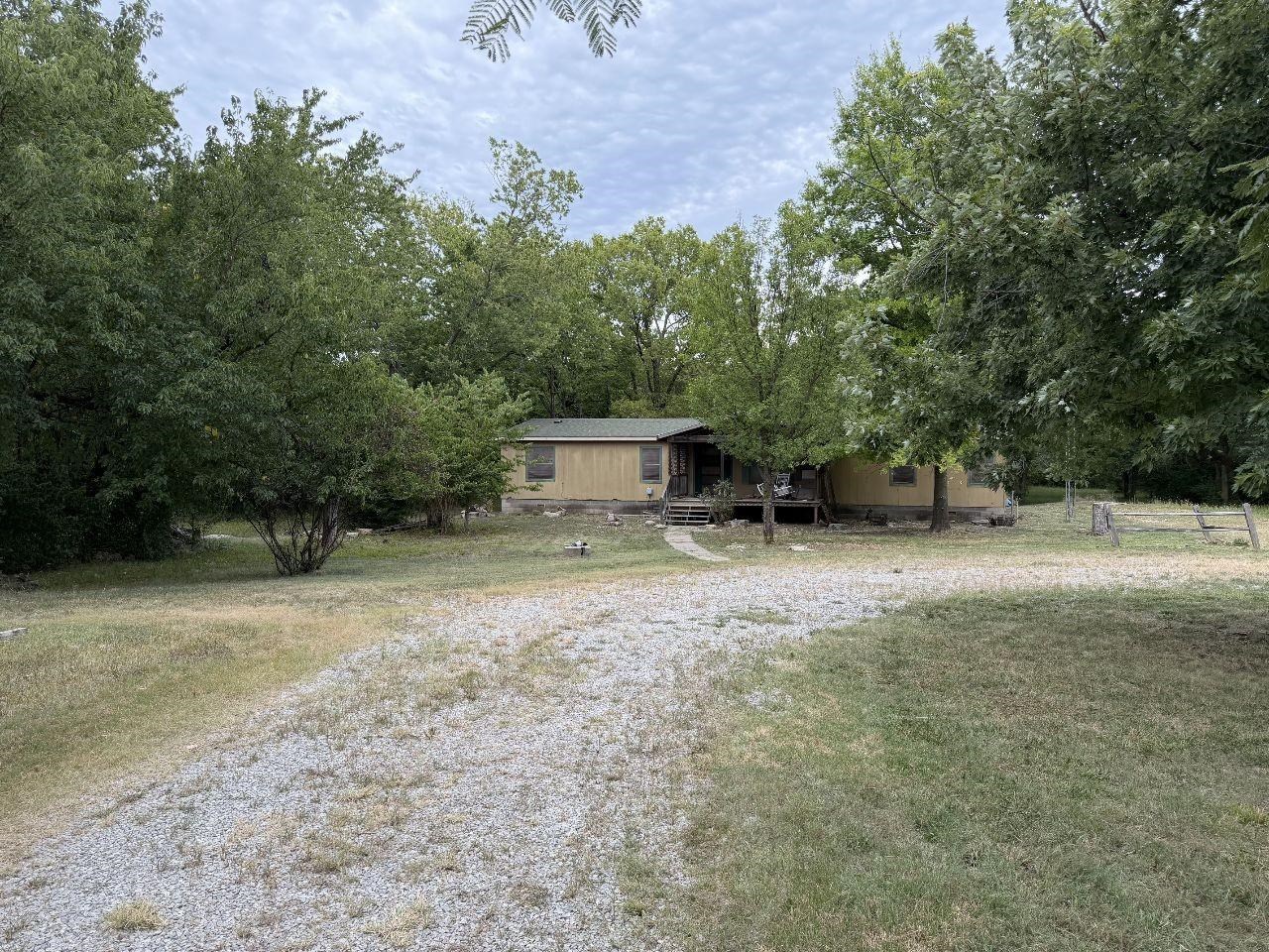 Looking for acreage close to the city and no dirt roads?  Drive out towards Augusta and leave the noise of the world behind. 10448 SW Tawakoni Rd offers a rare lifestyle centered on peace, privacy, and productivity. While it is conveniently located right off a paved road, this acreage is rare to find creating a natural fortress of absolute serenity. The defining crown jewel of this estate is its spectacular 9.7 acres of heavily wooded land.  Bring your tools or your architect! The property features a manufactured home requiring some work, offering the ideal canvas to renovate to your personal taste, or clear out to build your forever dream home surrounded by towering trees.  The groundwork for outdoor living is already laid with an existing horse corral, making it completely ready for your equine companions to explore the shaded forest trails. Imagine waking up to harvest fresh apples from your future orchard, gathering eggs from the chicken coop, or picking dinner straight from a massive backyard garden patch. Whether your goal is raising animals, cultivating fruit trees, or building from scratch, this acreage delivers. This property is truly a rare find.   Home is selling AS IS seller will make no repairs.  Please only conventional loans or cash only.