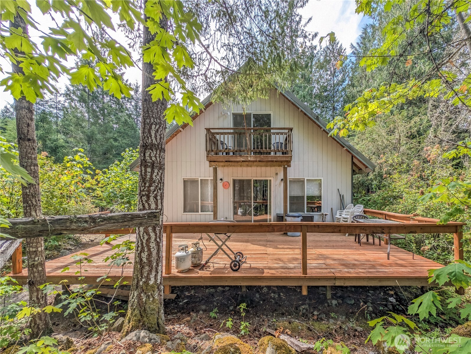 Turnkey Buttercreek cabin with +-130 ft of creekfront and expansive decks could be your own! Nestled on one of TWO included parcels for add'l building potential, this charming 3-bedroom, 2-bath chalet in High Valley features a blend of hardwood and tile floors, and included access to community pools, golf course, trails & clubhouse. Enjoy cozy evenings by the woodstove and an inviting kitchen. This cabin comes fully equipped with all appliances and furnishings, making it a true move-in ready gem. Conveniently located near Mount Rainier National Park, the vibrant mountain hub of Packwood, and the White Pass Ski Area, this property offers the perfect blend of tranquility and adventure. Embrace the mountain lifestyle today!