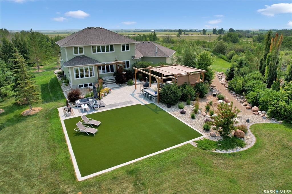 Welcome the perfect Saskatchewan paradise — an extraordinary 2-storey Westridge built home set on just over 5 beautifully landscaped acres, only 15 minutes from Saskatoon. This property offers the perfect blend of luxury, space, and outdoor lifestyle, with every detail thoughtfully designed for comfort and style. You'll be welcomed by the gorgeous East facing porch perfect for a morning coffee. Step through the grand front entrance into a bright, open interior filled with natural light. The open floor concept allows for the perfect family or entertaining setting. The kitchen's oversized island and gorgeous quartz countertop with a corner pantry make it the perfect space to cook and connect. The main floor features an office, large mudroom with laundry and a stunning primary bedroom retreat, complete with a spa-like ensuite and a spacious walk-in closet. Upstairs, you'll find three more bedrooms plus a large bonus room, offering plenty of space for family, guests and everything in between. Outside, the exquisite yard is an entertainer's paradise. Enjoy summer evenings with your very own outdoor kitchen, wood-fired pizza oven, and above-ground pool, all set against the backdrop of breathtaking Saskatchewan sunsets. A heated triple attached garage provides ample space for vehicles, toys, and tools, making this property as functional as it is beautiful.