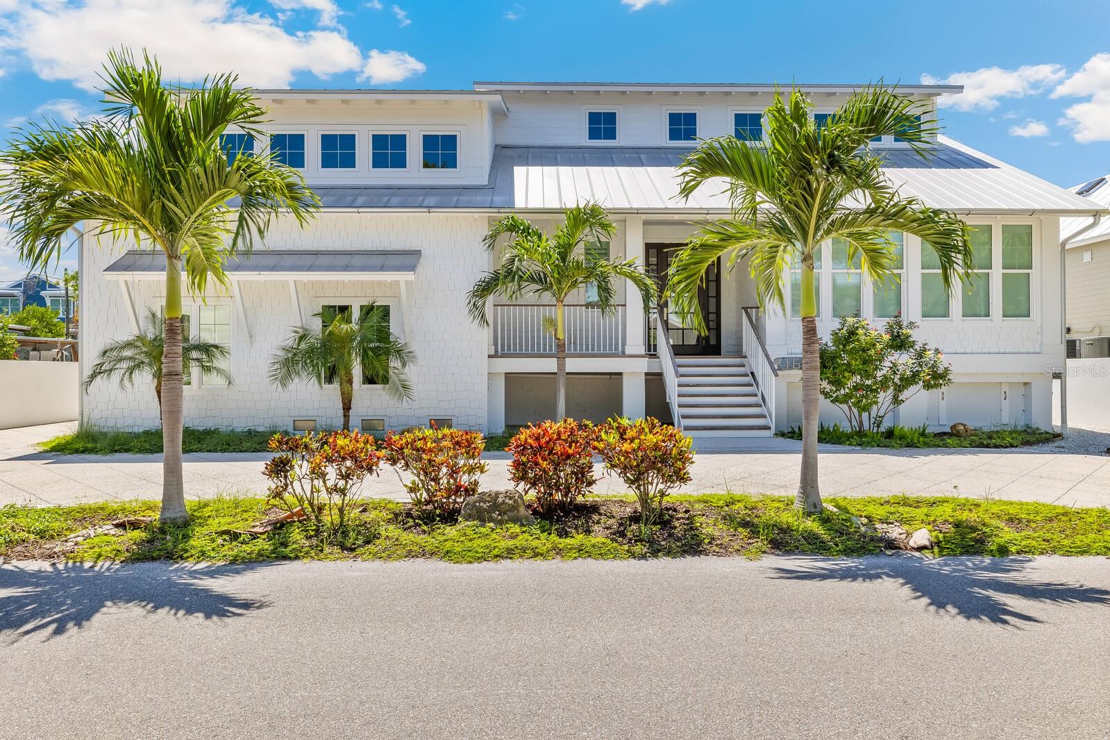 Welcome to an extraordinary coastal residence in the historic village of Boca Grande. This meticulously crafted home has an impressive 5,036 square feet, five bedrooms (the first-floor bedroom could be a den or office with direct access to a screened porch), and five bathrooms. This sturdy and elevated home on the natural “crown” of the island has not suffered any hurricane damage from wind or water. The home and the setting epitomize small island living. This remarkable home features an open floor plan, custom woodwork and oak flooring. The gourmet kitchen features professional-grade appliances including a Subzero refrigerator, a 4 burner Wolf stove with griddle, Miele wall steam oven, and an Asko dishwasher. A custom-designed breakfast bar, walk-in pantry, and an innovative Miele coffee bar cater to both daily living and elegant entertaining. This home features an 11’ curved “live edge” tiger maple bar with a bar sink, refrigerator, ice machine and custom cabinetry. Wine connoisseurs will appreciate the 100+ bottle custom chilled wine closet. The bar and adjoining lounge areas have LED “star constellation” lighting for a clean and enchanting ambiance. The bar and lounge look out through large disappearing sliding-glass doors to the coral stone patio, outdoor wood fireplace and canal, inviting seamless indoor-outdoor living with highly desirable southern exposure. Practical luxury abounds with an elevator, impact glass windows and doors, Hardi Plank siding, and a metal roof ensuring both comfort and security. The oversized garage accommodates both vehicles and a golf cart, perfect for exploring the charming village surroundings. The private den/office/bedroom, separate formal dining room, library, and bonus room offer versatile spaces for work and leisure. The home features a formal dining room that could be used alternatively as a music conservatory or a large, sunny office. There is a “bonus” room on the midlevel that has a full laundry with folding table and drying closet, a number of cleverly hidden spaces for storage, and a vaulted ceiling central space for work or leisure. The second floor features a gallery hallway and library with access to an outdoor balcony. For sailing or powerboat enthusiasts, the property's 80’ dock and 10,000-pound boat lift provide direct, deep-water access to Florida's pristine waters, without height-restrictive bridges. The home's location on the nearest canal to the center of town, offers boaters optimal convenience and privacy. The dock itself has a swim ladder and a custom-designed pivoting platform for safely launching small crafts like paddle boats, kayaks and SUP boards. Snook and other game fish can be caught right off the sunny dock, and the dock has a fish-cleaning station. Thoughtful additions include electric screens, a hidden wall safe nook, custom closet wooden built-ins, pocket doors, Plantation shutters, motion detection lighting, and innovative storage solutions demonstrate the meticulous attention to detail throughout this exceptional property. This residence stands as a testament to luxurious coastal living, where every element has been carefully considered to create an unparalleled living experience.