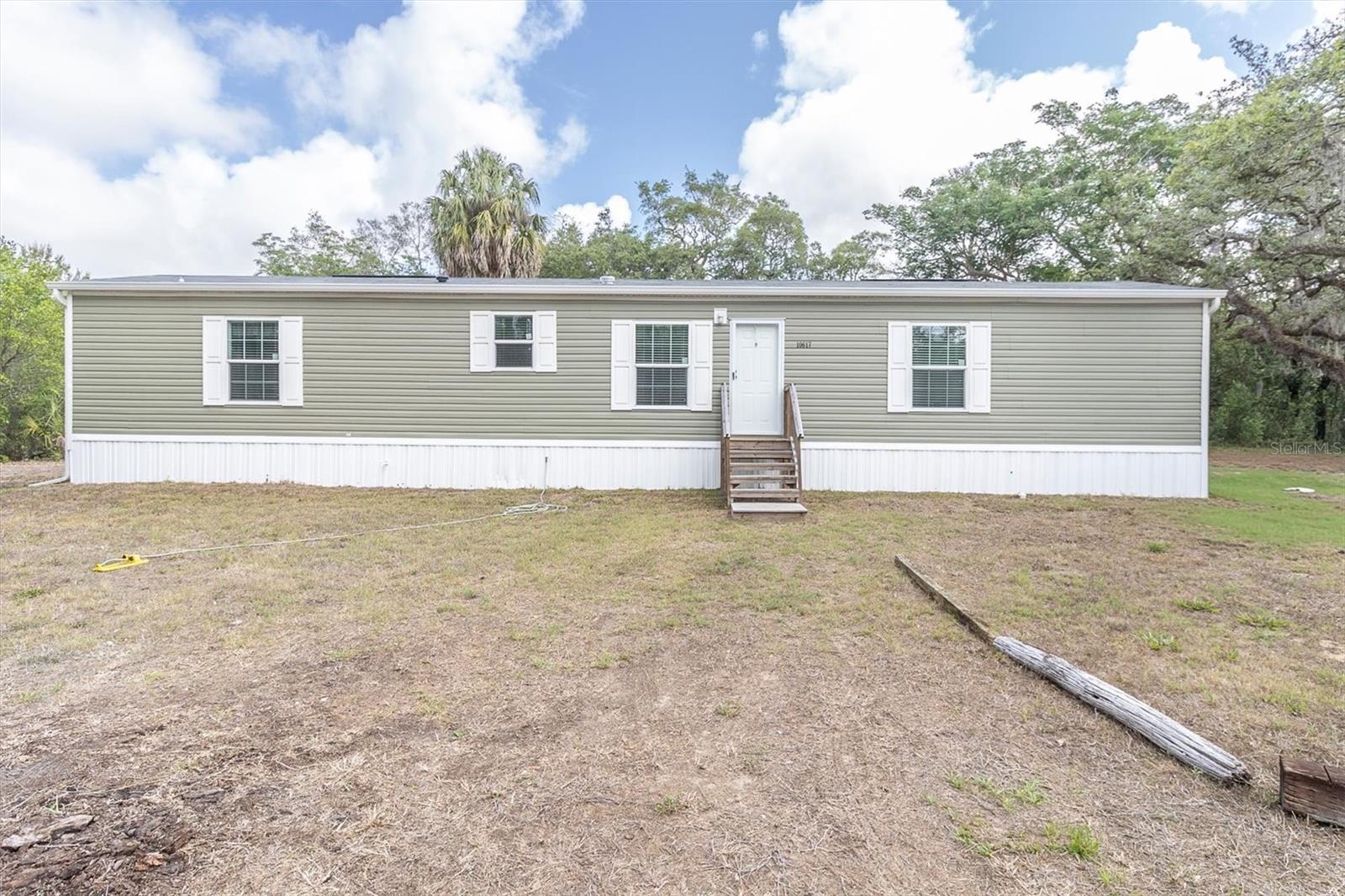 Manufactured home built in 2024 on 1.35 acres with an inground pool! Enjoy the perfect blend of modern comfort and country charm in this beautifully designed 3-bedroom, 2-bath home set on a spacious 1.35-acre lot. Step inside to an open-concept floor plan featuring abundant natural light from windows throughout and stylish laminate flooring for easy maintenance and a seamless flow. The spacious living room opens to a well-appointed kitchen complete with stainless steel appliances, ample cabinetry, and plenty of room for gathering and entertaining. The private primary suite offers a generously sized bedroom, walk-in closet, and an ensuite bath with a walk-in shower. Two additional bedrooms are thoughtfully positioned with a conveniently located second bathroom between them, providing comfort and privacy for family or guests. The laundry room, located just off the kitchen, includes a brand-new washer and dryer for added convenience. Step outside and enjoy the inground pool with patio area, perfect for relaxing, entertaining, and enjoying the Florida lifestyle year-round. Situated on the property is an additional commercial/residential building, offering endless possibilities for a home business, workshop, studio, guest space, or additional storage. With plenty of outdoor space to create your dream lifestyle, this move-in ready property combines versatility and functionality with peaceful acreage living.A short drive away is SunWest Park, a 70-acre waterfront park offering zip lining, wakeboarding, a beach area, picnic areas, and outdoor recreation. Hudson Beach Park is also nearby, providing additional opportunities to enjoy Florida’s beautiful Gulf Coast lifestyle. Restaurants, shopping, and medical facilities are conveniently located nearby, offering everyday convenience while still enjoying the privacy and space of acreage living.