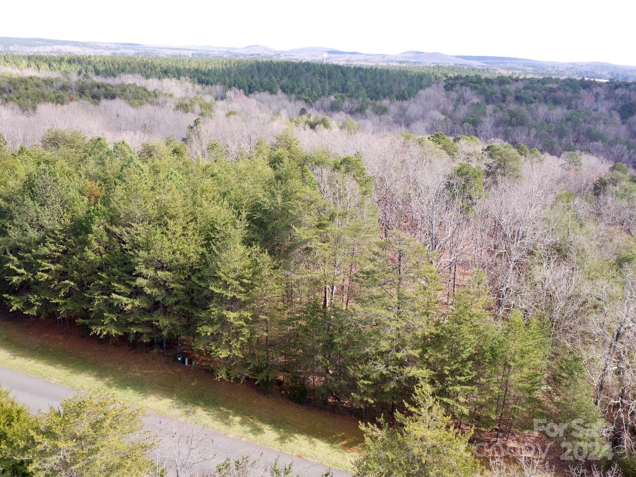 If you've been looking for a large building lot with awesome views of Badin Lake and the privacy of a gated community, look no further than this beautiful, wooded lot inside of the prestigious Heron Bay community. The community has a beautiful clubhouse, boat storage area, boat ramp and slips, and walking trails. This wooded lot is mostly level at the front and then slopes down toward the lake.  There is a beautiful view of the lake from this property.  At the back of the property, which is at the lake level, there is a small bit of water that extends from the lake. Heron Bay owners have the opportunity to join the adjacent Old North State Country Club, which offers a highly rated golf course, marina, club house, restaurant, pool, tennis courts & more.  Charlotte, Winston Salem and Greensboro are within an hour drive of Heron Bay, making it a perfect location for easy commuting to work.