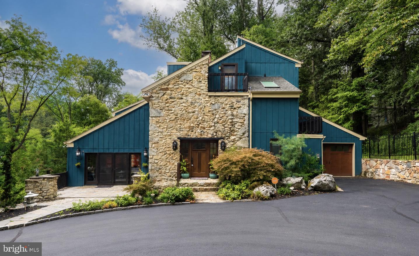 Welcome to 116 Oakwood Lane, a truly distinctive 5-bedroom, 3.5-bath residence that seamlessly blends historic character with contemporary living. The heart of this historic Valley Forge home is a circa-1770 stone farmhouse, thoughtfully incorporated into the architect’s design. The surrounding addition was creatively conceived to frame and complement the original farmhouse, drawing inspiration from the nation’s Bicentennial year in which the home was completed. Nestled along the side of Valley Forge Mountain on just under 4 acres, this private retreat is surrounded by mature woods and offers a peaceful, tranquil setting while remaining conveniently located near major commuting routes, shopping, and dining.As you enter, the home immediately makes an impression with its original fieldstone walls, exposed wood beams, hardwood floors, and striking stone fireplace—timeless details that showcase the character and history of the property. The living room continues to impress with soaring vaulted ceilings, skylights, and a stunning marble fireplace, creating a warm and inviting space filled with natural light.The living room flows effortlessly into the spacious kitchen, featuring stainless steel appliances, a large center island, and abundant cabinetry and counter space. Just beyond the kitchen, the family room offers another fireplace and direct access to the expansive rear deck, creating an ideal setting for everyday living and indoor-outdoor entertaining. A few steps up, the formal dining area provides an elegant space for hosting family and guests.Toward the front of the home, a private office showcases beamed ceilings and stone accent walls, while a cozy den or reading area offers a quiet place to unwind. A convenient powder room completes this level.Upstairs, the spacious primary suite is a true retreat, featuring beamed vaulted ceilings, your own private fireplace, a versatile bonus room, and an oversized walk-in closet complete with its own washer and dryer. The luxurious primary bath includes dual vanities and a walk-in glass-enclosed shower. Also on this level is a charming princess suite with a private full bath featuring a tub/shower combination. A unique secret door leads to the third bedroom, while an additional full bath provides convenience for the remaining bedrooms.The third level offers two additional bedrooms, providing flexibility for family, guests, or additional office space.The lower level adds an exceptional touch with a stunning stone wine cellar, complete with room for hundreds of bottles and a dedicated tasting area—an impressive feature for the wine enthusiast and an inviting space for entertaining.Outside, enjoy the expansive rear deck overlooking the private wooded grounds and lower stone patio, offering multiple areas for relaxing and entertaining. A front patio provides another peaceful spot to enjoy your morning coffee while taking in the serene surroundings.Additional highlights include two new HVAC systems, solar panels with a large solar battery system for electric storage, whole-house air filtration, a new 75-gallon hot water tank, solar skylights with interior shades, and fresh interior paint throughout the first floor.With its remarkable blend of original architectural details, thoughtful modern updates, expansive acreage, and exceptional privacy, 116 Oakwood Lane offers a rare opportunity to enjoy the character of a historic home with the comforts of contemporary living—all in a peaceful Valley Forge Mountain setting just minutes from everyday conveniences.