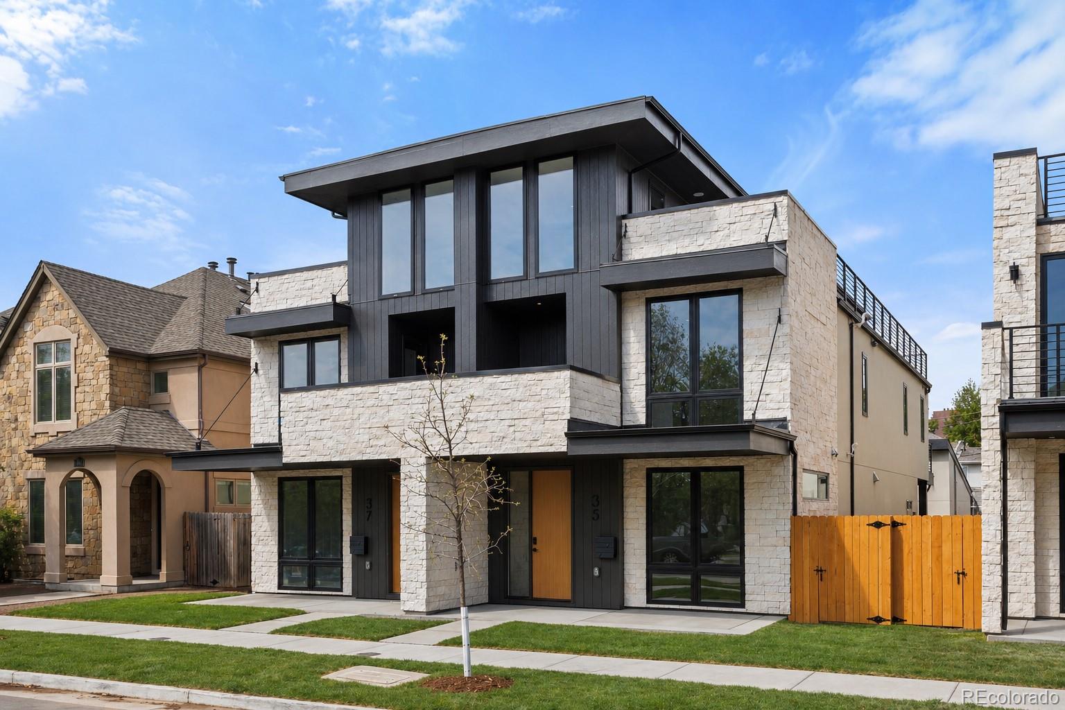This design-forward duplex located in Cherry Creek, reflects PBG’s commitment to thoughtful design and craftsmanship. Located less than a 10-minute walk from premier dining and boutiques, the 5-bedroom, 5-bath residence balances organic textures with clean, modern architecture. Most of the units from this project have gone under contract immediately! The exterior combines natural stone, dark wood accents, and crisp architectural lines for a timeless presence. Inside, wide-plank engineered white oak flooring and expansive windows define a light-filled, Modern Scandinavian-inspired interior, highlighted by matching interior stone accent walls and wood slat ceiling features. The main living space is anchored by a striking floor-to-ceiling stone and tile-wrapped gas fireplace. The chef’s kitchen serves as a true centerpiece with striking countertops in Porto Alegre, showcasing custom two-tone cabinetry, surrounded by Thermador appliances, extra cabinets on the kitchen island,  and butlers pantry. Upstairs, the primary suite offers a private balcony, gas fireplace, and wet bar. Spacious primary bath is defined by freestanding soaking tub, glass-enclosed dual-head shower, separate WC, and heated floors. A secondary en-suite bedroom and spacious laundry room complete the level. The rooftop level offers flexibility with a bedroom that can double as an office, an office, ¾ bath, wet bar, and expansive deck ideal for entertaining that supports a jacuzzi. The finished basement with soaring 10-foot ceilings expand the home with a recreation area, wet bar, full bath, additional bedroom, and optional fitness room/bedroom. A private backyard with covered patio, gas hookup, and TV prewire extends the indoor/outdoor lifestyle. Detached two-car garage includes 220V capability and optional storage. PBG industry leading 2-year builder’s warranty/8-year structural warranty. Prewired for speakers | No HOA |Buyer to Verify All Details Rooftop photos are from unit 25.