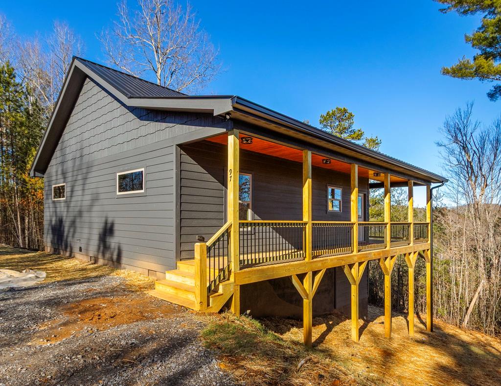 A new home by one of Murphy's best home builders! This charming single-level 2-bedroom, 2-bathroom cabin is BRAND NEW CONSTRUCTION on almost one wooded acre, just minutes from town. Designed for comfort and style, this home with LP smart siding offers easy access to the full-length covered porch on two sides of the home with a beautiful tongue and groove ceiling. Inside, the spacious Great Room features wide plank oak floors that extend throughout the home, a vaulted tongue-and-groove ceiling, and a cozy stone gas log fireplace, creating a warm, inviting gathering space. French glass doors open to the porch, blending indoor and outdoor living. The kitchen has granite countertops, a center island, and knotty pine cabinets. Both bedrooms are designed for comfort, with two full baths showcasing quality tile finishes. The exterior boasts a durable black metal roof and LP wood siding for long-lasting appeal and low maintenance. Hurry and make this home yours today!