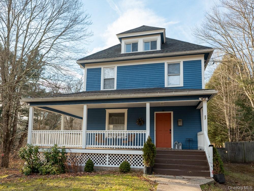 View of front facade with covered porch, roof with shingles, and fence