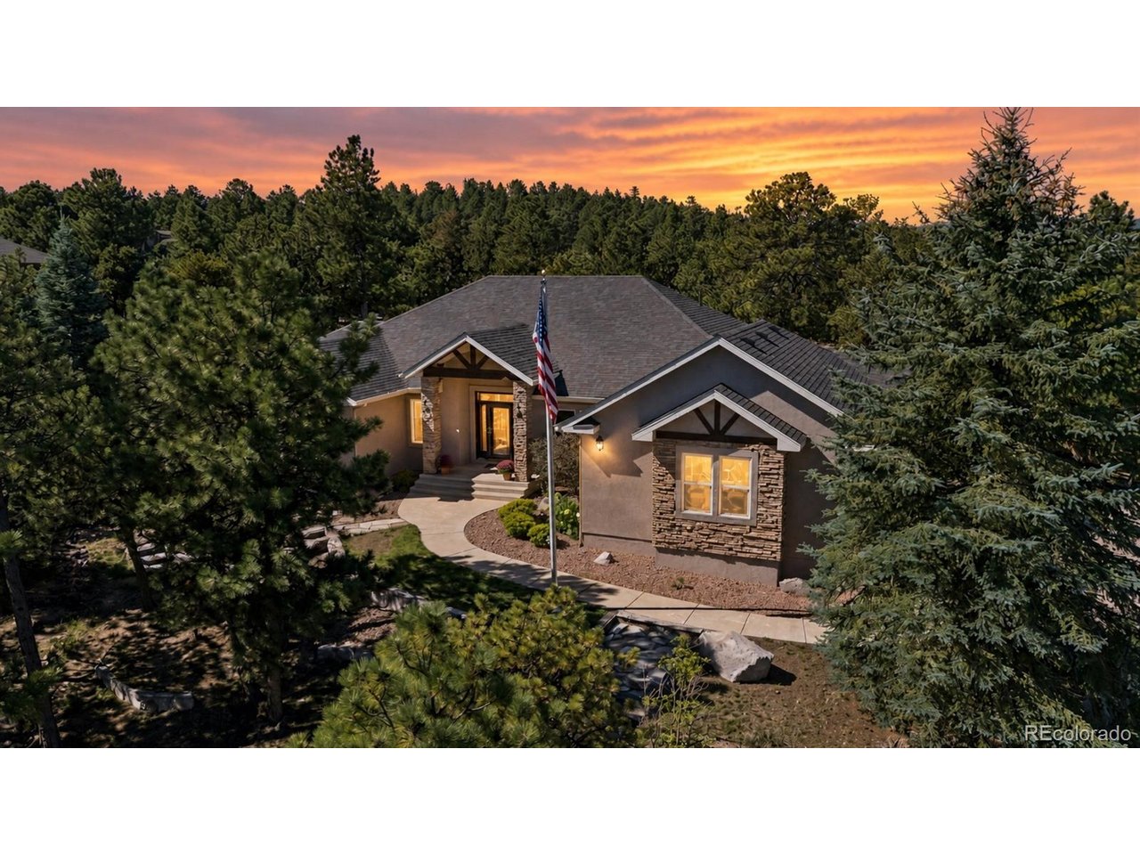 Stunning ranch-style home in Timberview at Monument, offering main-level living, exceptional privacy, and versatile multigenerational potential on nearly an acre of beautifully treed grounds in a quiet cul-de-sac. Hardwood floors lead to the inviting great room featuring soaring ceilings, expansive windows, and a stone fireplace. The spacious kitchen boasts abundant cabinetry with pullout shelves, generous counter space, stainless steel appliances, double ovens, walk-in pantry, and large island overlooking the dining area. French doors open to the main-level study, ideal situated as a quiet workspace. The primary suite offers deck access, a five-piece bathroom, and spacious walk-in closet. A secondary main-level bedroom and nearby full bath provides accommodations for family or guests. The beautifully finished lower level is ideal for multigenerational living or entertaining, featuring a sprawling family room with stone fireplace, impressive kitchenette and wet bar with quartz countertops, subway tile, abundant cabinetry, full-size refrigerator, dishwasher, and generous seating. Three spacious bedrooms, a Jack-and-Jill bath, additional three-quarter bath, and home theater with built-in speakers provide flexibility for guests, fitness, homeschooling, or office space. Enjoy the peaceful Colorado setting from the composite deck overlooking towering trees and a private backyard. Additional highlights include two HVAC systems with individual thermostats, two water heaters with instant hot water, two radon mitigation systems, newer appliances, updated window wells, extensive storage, laundry room with utility sink, and lower-level storage room with sink and additional laundry hookups, Generac Whole-House Generator. Located in the highly regarded Lewis-Palmer School District 38, this home provides convenient access to downtown Monument, shopping, dining, hiking and biking trails, and I-25 for easy commuting to Colorado Springs or Denver.