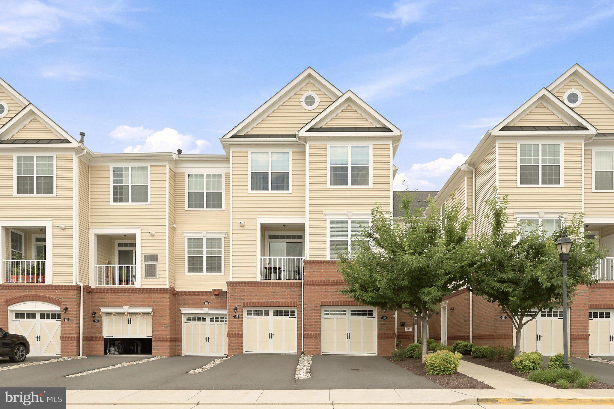 Welcome to this beautifully maintained Tennyson Model three-story condo townhome, built in 2020 and offering nearly 1,500 square feet of thoughtfully designed living space. Freshly painted throughout with brand-new carpet in the den, both staircases, and the entire bedroom level, this move-in ready home combines stylish finishes with everyday comfort in one of Ashburn's most convenient locations.The entry level welcomes you with hardwood flooring, a spacious foyer with a coat closet, and a versatile den that easily functions as a home office, fitness room, guest space, or hobby area. A one-car garage and deep driveway provides additional storage and convenient parking.The open-concept main level is filled with natural light and offers an inviting layout for both everyday living and entertaining. The beautifully appointed kitchen features granite countertops, white cabinetry, stainless steel appliances, gas cooking, a classic white subway tile backsplash, and abundant workspace for meal preparation. Elegant crown molding enhances the adjoining living and dining areas, while a private balcony provides the perfect place to enjoy your morning coffee or unwind in the evening, overlooking a peaceful tree buffer for added privacy. A conveniently located powder room with 12x12 tile flooring completes this level.Upstairs, both generously sized bedrooms feature their own private en-suite bathrooms, creating ideal accommodations for owners, guests, roommates, or multigenerational living. The bedroom-level laundry room includes a Samsung front-load washer and dryer for added convenience. Throughout the home, two-panel doors, brushed nickel hardware, and contemporary finishes create a clean, timeless aesthetic.Residents enjoy an exceptional amenity-rich lifestyle with access to three community pools, two fitness centers, tot lots, playgrounds, and miles of scenic walking and jogging trails. Ideally located just off Loudoun County Parkway, the home is less than two miles from Brambleton Town Center, Dulles Landing Shopping Center, and the Ashburn Silver Line Metro Station. Major commuter routes, park-and-ride options, shopping, dining, entertainment, and highly rated schools are all just minutes away, making this an outstanding opportunity to enjoy low-maintenance living in the heart of Ashburn.