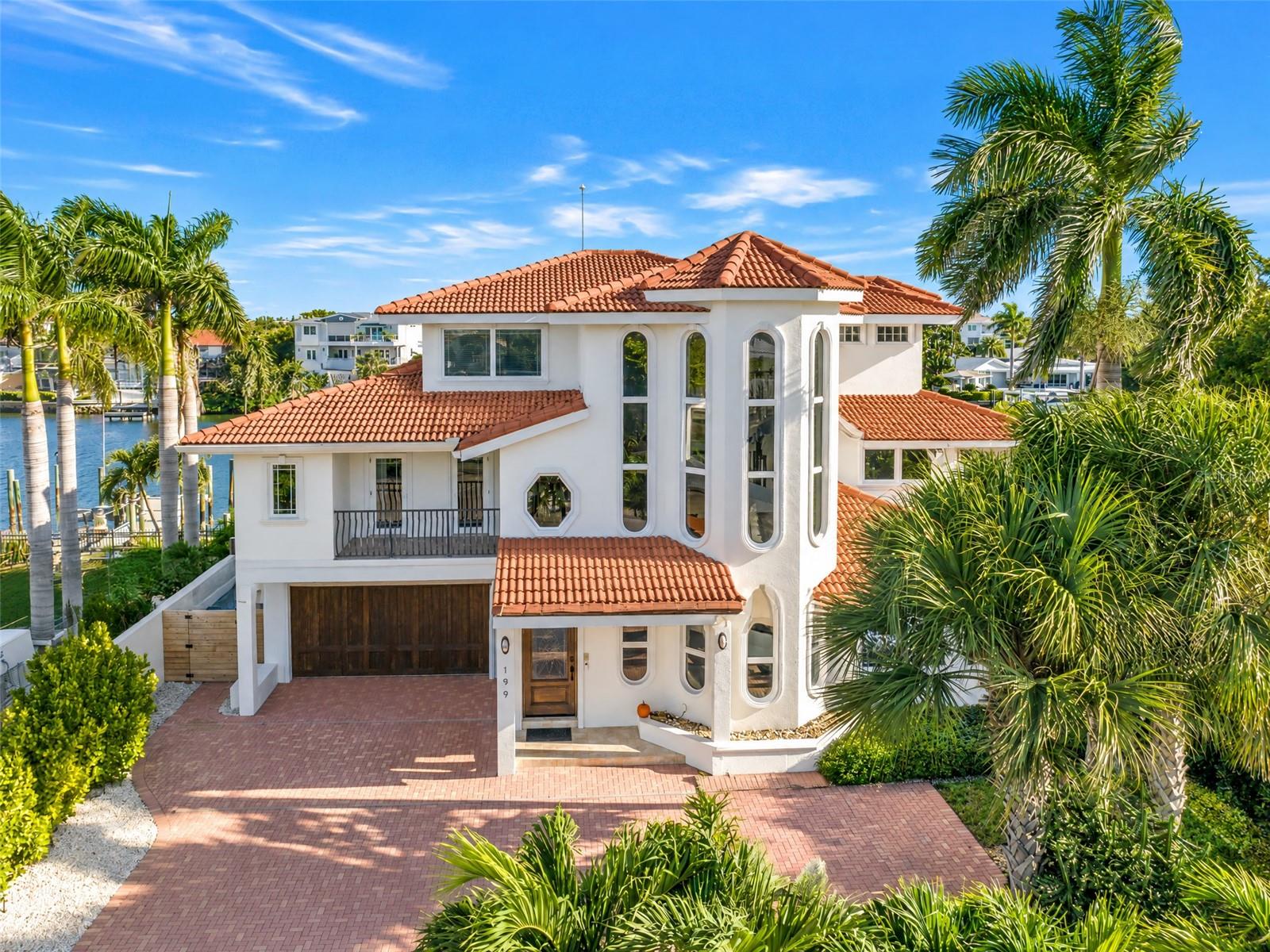 Escape to the sought-after island of Vina Del Mar in Pass-a-Grille, where a short stroll puts your toes in the sand at one of the finest beaches in St. Petersburg. Set in FEMA flood zone X500, this elevated three-level waterfront estate stayed completely dry through the 2024 hurricane season, even the pool, so you can enjoy island living with confidence. Step into the elevator and glide to every level of a home designed for effortless luxury. The brand-new 2026 kitchen is a true showpiece, with stainless steel Thermador appliances, a pot filler above the range, new stone countertops with a dramatic waterfall backsplash, and an island with a separate prep sink. The living room soars with 23-foot ceilings, a built-in surround sound system, and warm cove lighting, a perfect backdrop for movie nights and memorable gatherings. The ground level features an en-suite bedroom, an office that doubles as a guest room, and a large bonus area with a wet bar and wine fridge made for entertaining and ample storage. Upstairs, the second level offers three additional bedrooms, including one en-suite with balcony access, plus the main laundry. The third level is home to a versatile loft and a private primary retreat with its own refrigerator and wet bar, double vanity, walk-in shower, water closet, indulgent Jacuzzi tub, and a washer and dryer. Outside, the resort-style pool shimmers with iridescent tile and is ready for year-round enjoyment with a new gas heater, an electric heater, and a new spa pump. Boaters and anglers will be captivated by the composite dock with 20,000 lb and 13,000 lb lifts and a fish cleaning station, ready for your biggest vessel and your best catch. Whole-home generator (2026), a large buried propane tank, three A/C units, an attic dehumidifier, and an ADT security system provide lasting peace of mind. The epoxy-floored garage is a rare find on the island, with space for two cars plus a golf cart and a rear door opening to the backyard. Coastal living, elevated. Schedule your private showing today.