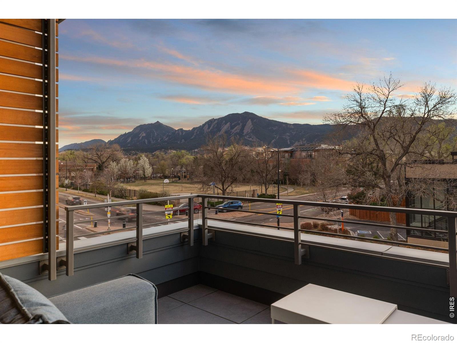 Experience the pinnacle of modern Boulder living in this exceptional, low-maintenance dwelling, where architectural sophistication meets unobstructed Front Range views. Part of the exclusive Flatiron Vista collection, this home lives like a single-family residence, featuring a private entrance, forecourt gardens, & a striking facade of cedar, metal, & stucco. Inside, walls of windows bathe the open-concept floor plan in natural light, seamlessly connecting the chef's kitchen to the spacious living & dining areas. The interior has been thoughtfully elevated with high-end designer touches, including a custom floating media console with integrated lighting & a 75-inch framed TV with concealed wiring for a sleek, gallery-like aesthetic. The living experience spans three meticulously planned levels, each with designated outdoor space. Smart home technology manages the convenience of custom motorized shades throughout, alongside Kasa smart lighting & a comprehensive Ring security suite. The primary suite is a luxurious haven, boasting a spa-inspired bathroom & an expansive walk-in closet with custom organization & soft-close cabinetry. Two secondary bedrooms feature premium Elfa shelving complimented by the high-performance LG steam laundry center. Entertainment reaches new heights in the top-floor family room and its adjacent jaw-dropping rooftop terrace. Complete with a wet bar, floating shelving, & natural gas connection, this space is perfectly equipped for sunset grilling or cozy evenings against the backdrop of the iconic Flatirons. Extra storage & a private, detached garage showcasing an electric car lift for 2-car garage parking downtown add to the convenience and functionality of the modern design. The phenomenal central location is walking distance to the Google campus, Pearl Street Mall, & staples like Whole Foods & Target, with growing, vibrant surroundings. This home offers an unparalleled urban lifestyle with the quiet luxury of a private retreat.
