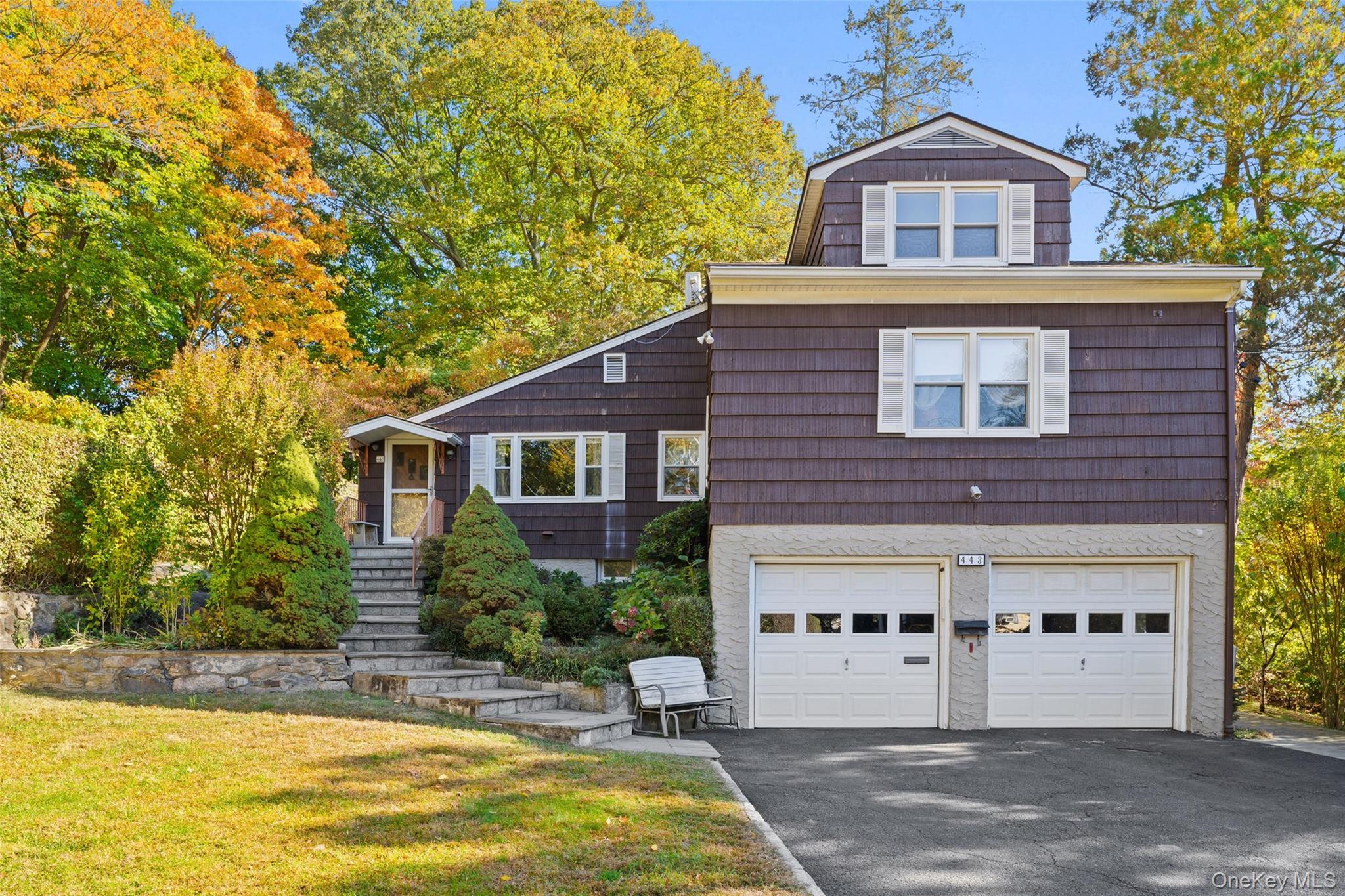 Lovingly maintained by the same family since 1967, this spacious home is ready for its next chapter. Located in the vibrant village of Tarrytown—not far from the Metro-North station, the acclaimed Main Street’s eclectic mix of eateries, caf&#233;s, and galleries, and the scenic Hudson River waterfront—this property offers both convenience and charm.
Set against the peaceful backdrop of Hackley School’s fields and grounds, the home enjoys a sense of privacy rarely found in such a central location. Inside, you’ll find 2,647 sq ft of living space with incredible potential to update and customize to your taste. The main level features 3 bedrooms and 3 full baths, including a generous primary ensuite with a handicapped-accessible bathroom. Upstairs, a fourth bedroom, third full bath, and a large loft area with a small kitchenette offer flexible space for guests, extended family, or a home office suite. The full walkout basement provides even more possibilities—complete with a small summer kitchen/workshop, a cozy den with a wood-burning fireplace, and direct access to both the side yard and garages. With its versatile layout, this home is ideal for multigenerational living or creative reimagining. Additional highlights include central air conditioning, baseboard heating, a two-car garage, bluestone walkways, a rear wooden deck and a fenced garden in the front corner of the property—perfect for those with a green thumb. With its solid bones and convenient location, this is a great opportunity to create your dream home in one of Westchester’s most sought-after river towns.