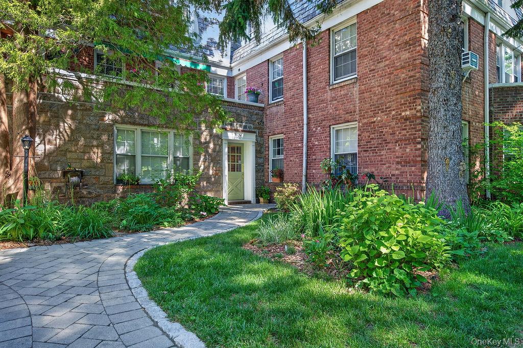 Lovely, private complex, surrounded by green space and trees. Quiet location, yet only a mile to the train station.  First floor unit - NO STEPS!  Plenty of parking for residents and guests. This corner unit, with lots of windows brings in an abundant amount of light and provides wonderful cross ventilation.  There is a useful built-in cabinet and shelves and a working wood-burning fireplace in the spacious living room for those chilly days and nights.  Harwood flooring in the entry, living room, dining area and hallway is in great shape!  The very large corner bedroom has 2 closets and a second floor views on two sides.  The bedroom and bathroom are located away from the main living area, and there is a bonus room with access to the kitchen and living room, which is large enough to be used as an office, a 2nd bedroom, TV room or dining room, though there is space for a large dining table off the entry.  The Hartsdale Village and train is just a mile away.  Right outside your door, and part of the complex, you have a playground and area to grill and gather. Laundry and storage is right in the basement of the building.  Parking is plentiful, free and unassigned, and there is a waitlist for a garage space if desired.