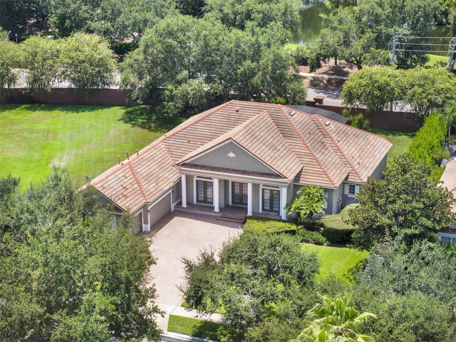 Tucked away in the prestigious guard-gated community of The Reserve at Lake Butler Sound, this exceptional 4-bedroom, 3.5-bath single-storypool home blends timeless Mediterranean style with modern sophistication. Set on over half an acre in a quiet cul-de-sac, the home welcomesyou with a paver driveway, lush mature landscaping, and an elegant entry framed by architectural columns. As you enter through the grandbeveled glass French doors, you’re immediately greeted by soaring cathedral ceilings and sweeping views through the family room to thescreened pool and spa beyond. The formal living and dining areas feature stately archways, tray ceilings, and designer lighting, creating arefined space for entertaining. The heart of the home is the gourmet kitchen, designed with the chef in mind. Outfitted with granite countertops,a large breakfast bar, and a sunny dinette space, it flows effortlessly into the family room where a natural gas fireplace and rich wood floors addwarmth and charm. The spacious Owners Suite is tucked away for privacy, offering a tranquil retreat with travertine flooring, dual walk-inclosets, a luxurious ensuite bath with double vanities, a large walk-in shower with dual heads, and a built-in wet bar. A flexible sitting area justoutside the suite can serve as a home office, reading nook, or nursery. Bedrooms two, three, and four offer generous space and privacy,including a jack-and-jill bath and an additional full hallway bath. A dedicated office near the front of the home can easily serve as a fifth bedroomif needed. Additional highlights include a powder room, oversized laundry room, and a 3-car courtyard-style garage. Unwind on the ceramic-tiledpool deck surrounded by tranquil landscaping and dramatic lighting, offering a peaceful backdrop for evenings outdoors. Residents enjoyexclusive access to a community fishing pier on Lake Butler and a charming garden park, all just minutes from top-rated public and privateschools, downtown Windermere, major roadways, Disney, and upscale shopping and dining.