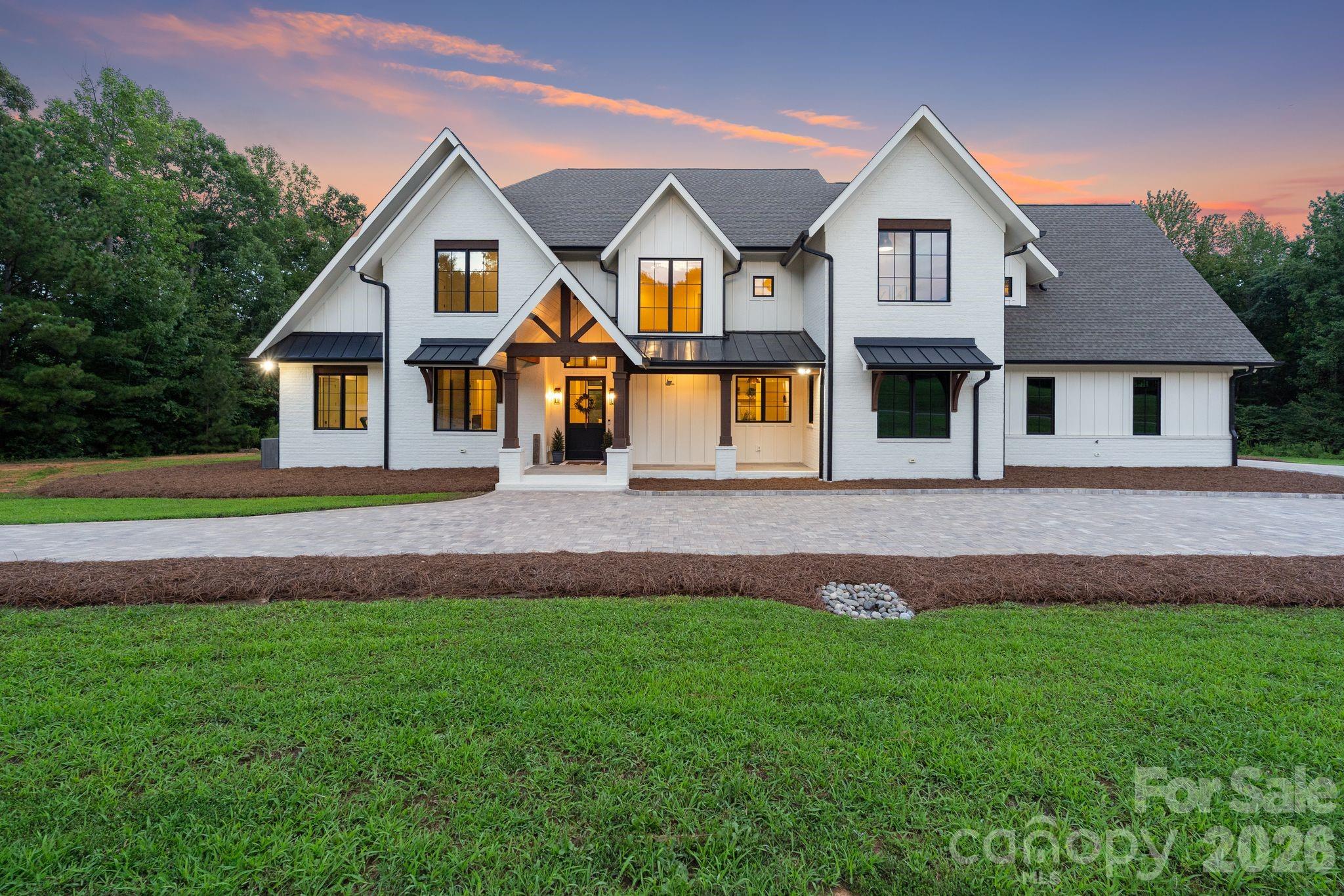 Welcome to 2905 McNeely Farms Drive—a masterpiece of modern farmhouse design spanning 5,400 square feet of meticulously crafted luxury. From the custom paver driveway to the sprawling, sun-drenched living spaces, no detail has been overlooked.The main level boasts soaring vaulted ceilings across an open-concept layout built for effortless entertaining. At the heart of the home, the chef’s kitchen features a 10-foot quartzite island, a butler’s pantry with handmade Moroccan tile, and reverse-osmosis filtration. Panoramic sliding doors open directly to a sweeping covered patio complete with an outdoor fireplace—creating a seamless indoor-outdoor living experience.The main-floor primary retreat is a private sanctuary featuring 20-foot vaulted ceilings, an electric fireplace, dual walk-in closets, a spa-inspired bath, and direct patio access. A dedicated home office, private fitness room, and custom laundry room round out the main floor.Upstairs, four individually designed guest bedrooms offer optimal natural light, custom fixtures, and en-suite baths adorned in Calacatta marble and bespoke cabinetry. The second level also features a massive media room, a second bonus/game room, and a powder room.Key Features & AmenitiesMain Level Luxury: Primary suite on main, dedicated home office, private gym, and high-end laundry room.Gourmet Kitchen: 10 ft quartzite island, butler’s pantry, handmade tile, and reverse osmosis water system.Exceptional Outdoor Living: Two covered patio spaces, fireplace, and a secluded backyard ready for custom additions.Tradesman/Collector Garage: Nearly 1,200 sq. ft. ventilated space featuring a dedicated workshop and private half bath.Property Details: Encapsulated crawlspace with dehumidifier, high-yield private well, and no HOA fees.Prime Location: 5 minutes to historic downtown Waxhaw with access to a neighborhood equestrian boarding facility.Schedule your private tour today to experience this unparalleled blend of elegance, seclusion, and craftsmanship.