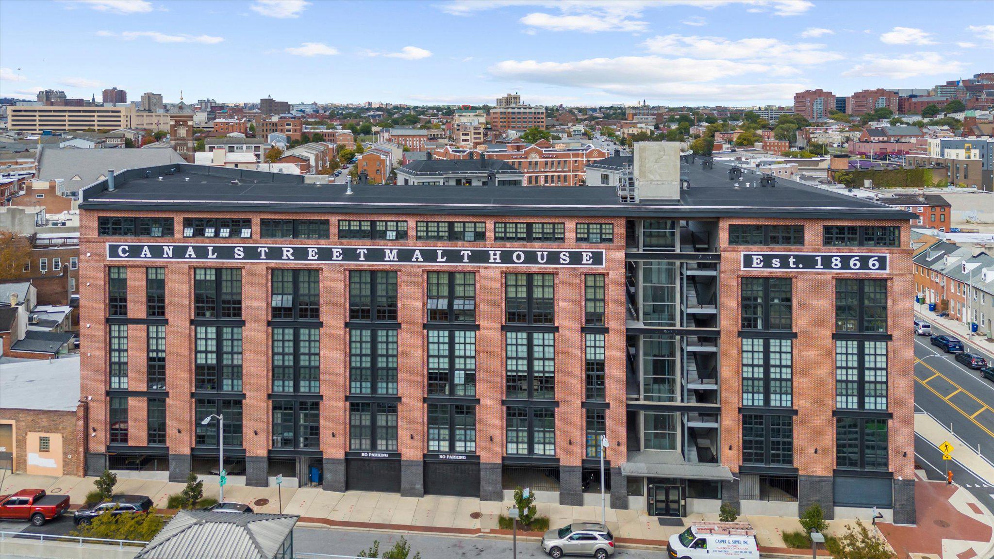 There’s a certain ease to life here, where light pours in, the city feels within reach, and every detail has been thoughtfully considered.Ideally located on the fourth floor of the Canal Street Malt House, this residence is defined by its dramatic floor-to-ceiling windows, framing captivating views of the Harbor East skyline. From morning light to evening glow, the home is constantly shifting in the most beautiful way; bright, open, and effortlessly inviting.The main level is designed for both everyday living and entertaining, anchored by a chef’s kitchen complete with a Wolf range, wine refrigerator, and an expansive island that naturally becomes the heart of the home. A main-level ensuite bedroom offers flexibility and comfort, whether for guests or a more private retreat.The second-floor primary suite feels like its own quiet escape. Lofted and open, yet deeply private. Thoughtfully scaled, it features an expansive walk-in closet and a spa-inspired bath with a soaking tub, creating a place to truly unwind at the end of the day. Just beyond, a spacious balcony overlooks the building’s landscaped courtyard; an unexpectedly serene backdrop in the middle of Little Italy. Throughout, generous proportions set this residence apart as one of the larger floor plans in the building, offering a sense of space that’s increasingly rare in city condo living.Garage parking with one assigned space adds a layer of convenience to an already elevated lifestyle.See why the Canal Street Malt House is one of the most coveted addresses in Baltimore. In the heart of Little Italy, a few blocks from Harbor East, waterfront promenades, and some of Baltimore’s most beloved dining destinations, this is city living at its most refined.