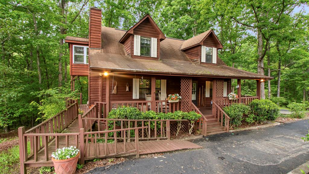 This 3-bedroom, 3-bath cedar-sided cabin with a workshop sits on nearly an acre in the quiet and established Peachtree Hills community (close to Erlanger hospital) offers a rare combination of space, privacy, and versatility. A paved circular driveway leads to the full-length covered front porch, complete with a ramp for easy access. Inside, the Great Room features a soaring ceiling and a floor-to-ceiling gas-log fireplace, creating a warm and inviting central space, while a second living area adds even more room to relax. The dining room impresses with its vaulted wood ceiling and floor-to-ceiling windows that fill the space with natural light. The functional kitchen sits at the heart of the home, flanked by two guest bedrooms that share a Jack-and-Jill bath. One of those bedrooms and the adjoining sunroom open to a screened back porch overlooking the peaceful yard. Upstairs, the private primary suite includes a vaulted ceiling, reading nook, and en-suite bath with double vanities, while a large bonus room and sunroom offer flexible space for a home office, hobby room, or playroom. The lower level includes a garage, additional bonus room, and plenty of storage. The real bonus is the massive 36' x 30' workshop with power and a roll-up door—perfect for a wood shop, equipment storage, or just about any project you can imagine. With multiple porches and quiet outdoor living areas, this home is full of potential and priced to let you make it your own. Call us to see it today—great value homes like this don't come around often!