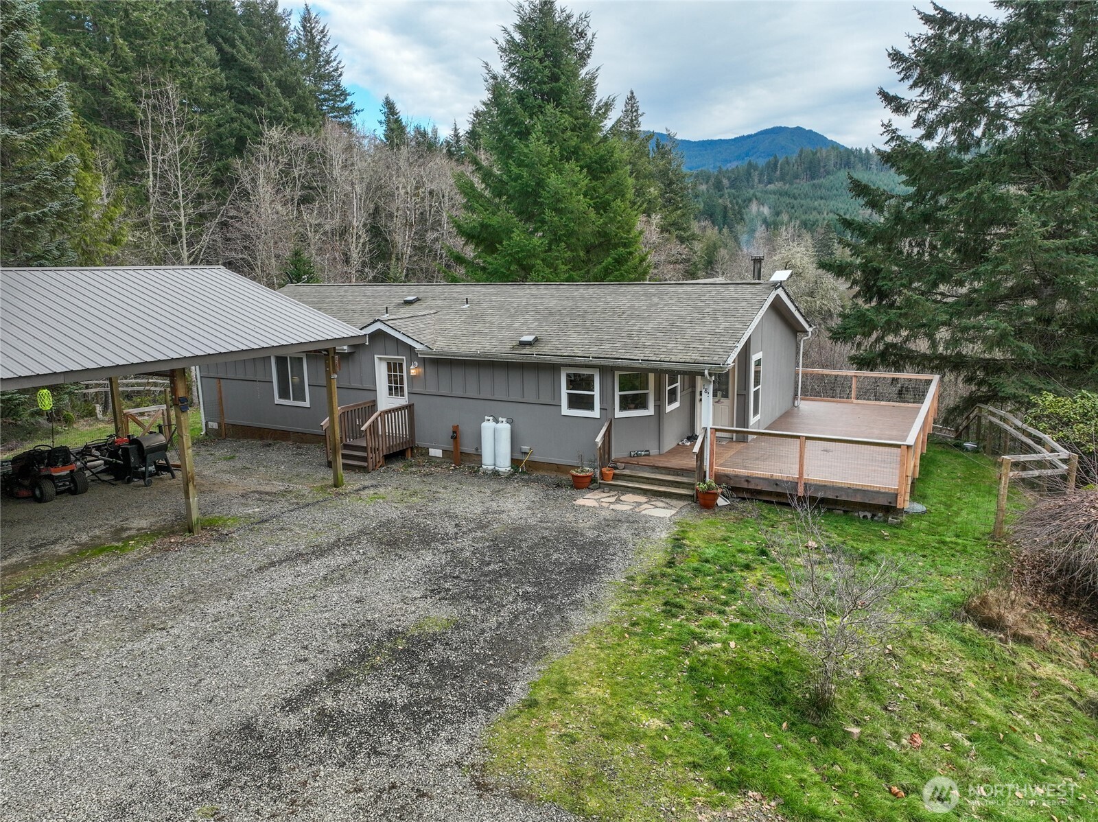 Come home to your own PNW Retreat on 5 private acres with a view of Burley Mountain! This 2-bedroom, 2-bath home is beautifully updated with new appliances and a fully updated kitchen. Lovely stone touches have been added behind the gas range and woodstove. New matching LVP flooring throughout and a spacious partial wrap around deck has been built. Three bedroom septic means you could possible convert the den to a third bedroom or add a small guest suite or ADU for more sleeping space. Large 30x42 detached garage/workshop has a nice 14 x 30 carport for your yard implements or vehicle AND there is an oversized 26 x 36 carport right at the utility room entrance door. Well built chicken coop, mature orchard, fenced garden space, and newly installed greenhouse could make your private homestead dreams come true. Seasonal creek wanders through the property. Enjoy the well established landscaping. Great southern exposure for light year round. Close to Gifford Pinchot access and surrounded by wildlife.