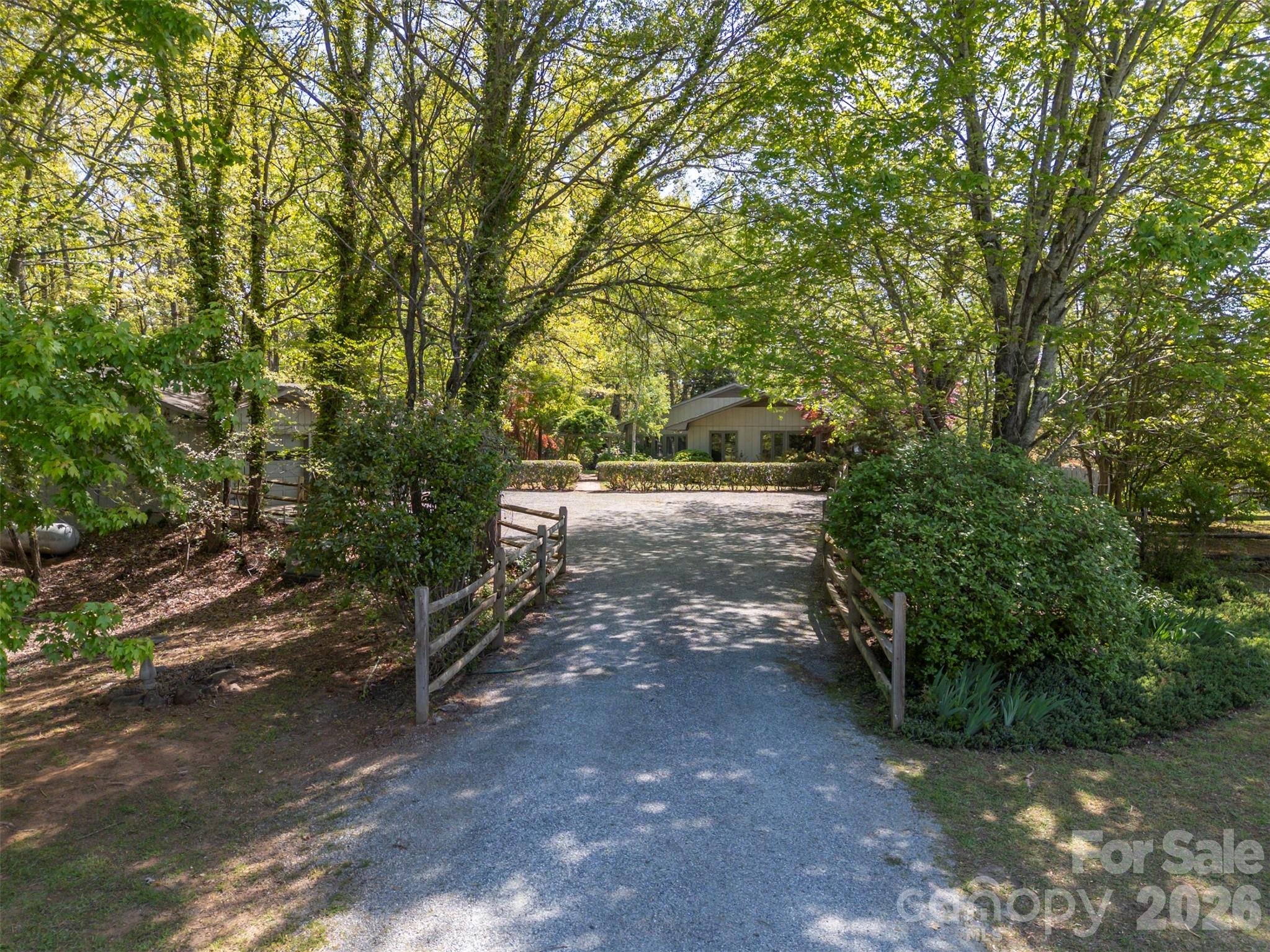 Tucked along a private drive in the sought-after Hunting Wood community, this Tryon retreat on 9.6 acres offers the rare combination of extensive, one-level living space, privacy, and “lifestyle” amenities. The main residence features 3,125 heated sq ft with 8 natural light-filled rooms, 4 bedrooms, and 3.5 baths, plus a 603 sq ft finished basement. Enjoy cozy evenings by the fireplace, then step outside to a property designed for everyday living and effortless entertaining. The grounds are a woodland retreat: brick walkways, a vine-draped arbor, wooded garden paths, and a tranquil water garden/pond create a peaceful, storybook setting. Out back, there's a large covered porch with a hot tub and a fenced yard for the dogs. Summer becomes a staycation with the in-ground swimming pool and expansive pool deck—perfect for gatherings, lounging, and outdoor dining. For hobbyists and creatives, the property shines with a detached garage with separate dedicated wood shop, a small greenhouse, and an additional artist studio—a true compound for work, play, and inspiration.Move-in with confidence: the sellers completed a pre-inspection and proactively addressed the maintenance items identified—delivering a home that feels cared for from top to bottom. In addition to a list of minor items addressed, major improvements include a new roof and crawl space encapsulation. If you’re looking for a home that offers privacy, character, and resort-style amenities—plus the peace of mind of thorough proactive maintenance—this is a must-see.