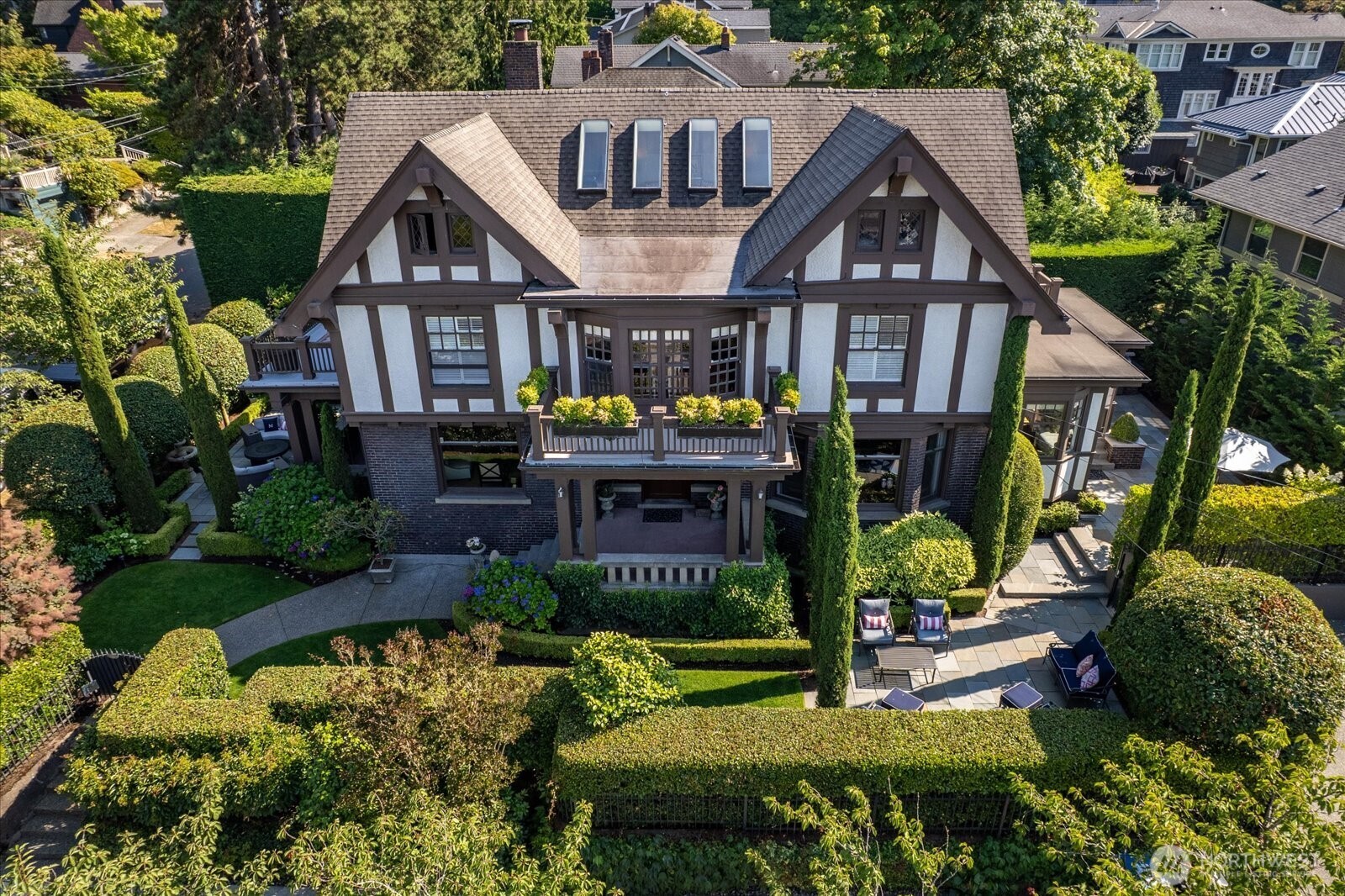 Perched on coveted Capitol Hill, this commanding 3-story Tudor blends timeless architectural grandeur with elite modern luxury. Originally built in 1911 and meticulously updated in 2019, the home retains extensive period charm with all the benefits of modern living. The expansive layout features 5 bedrooms and 5 bathrooms, highlighted by a chef's kitchen with top-of-the-line appliances including Lacanche, Sub Zero and Miele. Floor-to-ceiling vistas showcase breathtaking, views of Lake Washington, Husky Stadium, and the Cascade Mountains.  Perfect for the professional couple or a growing family, this generational home comes complete with a full mother-in-law quarters featuring a bathroom, kitchen, expansive living spaces and wine cellar.  Incredible outdoor entertaining spaces and grand formal rooms offer an exceptional scale that can easily host 100 guests for unforgettable events. When venturing out, enjoy seamless access to local landmarks and destination eateries such as D’ LaSanta, South Lake Union, the Seattle Center and Pike Place Market.  Experience unparalleled Pacific Northwest living in one of Seattle’s most iconic neighborhoods.