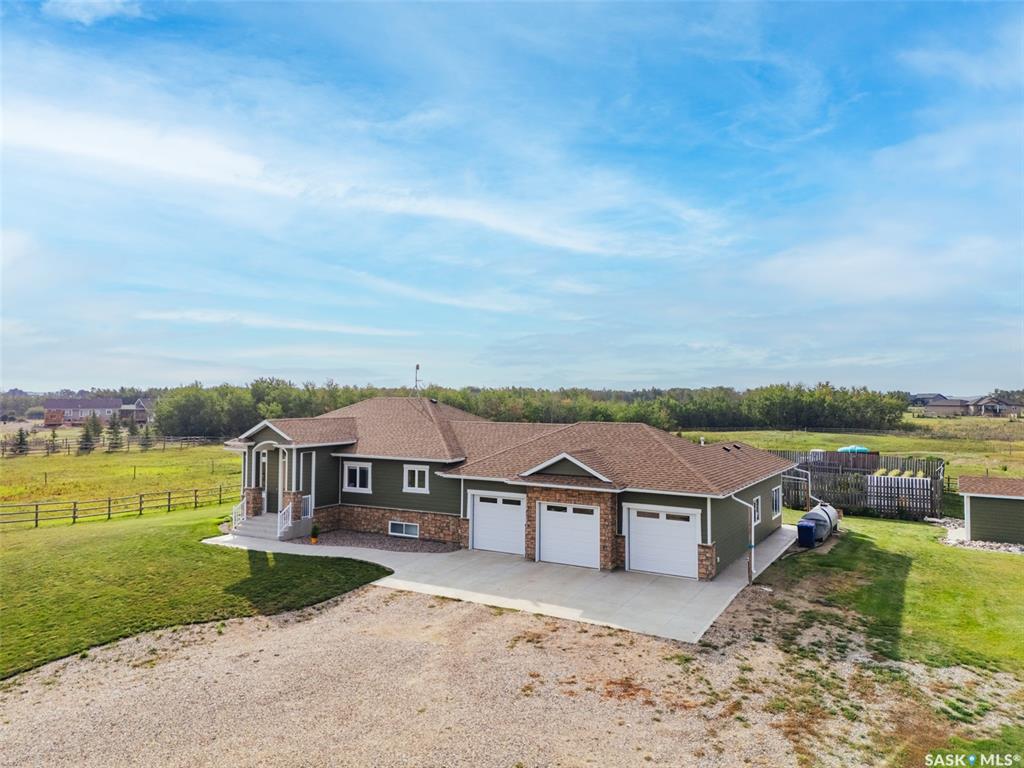 Welcome to 118 Louise Crescent in the coveted acreage community of Cherry Hills — just 15 minutes from Saskatoon’s edge. This 1,502 sq. ft. executive bungalow is a stunning blend of modern design, smart functionality, and country charm. Step inside to discover a bright, open-concept main floor with an exceptional window package that floods the home with natural light. The spacious living room, dining area, and kitchen flow seamlessly under a vaulted ceiling, creating the perfect setting for entertaining or relaxing. The kitchen features quartz countertops, a corner pantry, roll-out drawers, stainless steal appliances. The dining room can easily seat a large extended family for holiday meals and the gas fireplace in the adjoining living room makes for cozy evenings. Hardwood runs throughout the main level, and a covered deck off the dining area allows for year-round BBQ. The primary suite is a lovely retreat, offering a large walk-in closet and an ensuite with a soaker tub beneath a privacy rain-glass window, heated floors, and a walk-in shower. A 2nd large bedroom (or office), another 4-piece bath, and a spacious mudroom/laundry room with built-in cabinetry, quartz countertops, and deep utility sink complete the main floor — all leading to an oversized triple-car garage with a separate workshop bay and a sunlit all-season greenhouse.The fully finished basement features a large family and games area, 2 more bedrooms, 4-piece bath, and a vented cold storage room perfect for preserves or wine. Outside, the 7.14 acre property is 3/4 fenced with treated rail fencing, hotwired, & divided into five paddocks with a 4-season watering bowl sourced by underground lines. Mature spruce trees border the property, and there’s a drive-in garden shed, an adorable matching horse barn, and 2 fully developed gardens with direct waterlines. Complete with central air, central vac, and window coverings, this Cherry Hills acreage offers comfort with country serenity — a truly rare find.