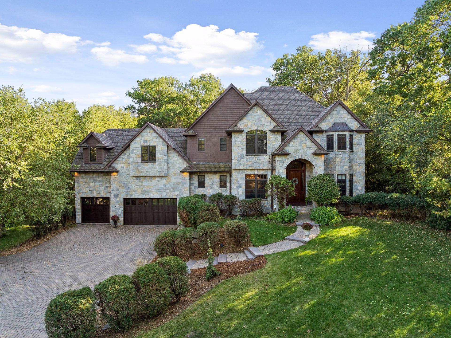 Experience the perfect harmony of elegance, innovation, and nature in this secluded 1.5-acre wooded estate nestled between Anderson Lake, Bush Lake and the 1,100-acre Hyland Lake Park Reserve. Crafted with Venetian plaster walls, Bolivian rosewood floors, and freshly painted interiors, every space radiates timeless sophistication. The chef’s kitchen, equipped with Wolf and Sub-Zero appliances, a massive honed granite center island, and a butler’s pantry, sets the stage for inspired entertaining. A main-floor office provides a refined workspace, while the lower level offers a home theater, wet bar, fireplace, and guest suite with private bath and walkout to a flagstone patio. Enjoy effortless indoor-outdoor living with a summer screen porch and expansive deck overlooking a gated, pet-friendly backyard with abundant wildlife. Each upper-level bedroom features its own bath, and the primary suite boasts a spa-inspired ensuite with heated floors. Exquisite smart home with solar panels, EV charging, and proximity to MSP International Airport, this  prestigious West Bloomington estate blends luxury, privacy, and convenience.