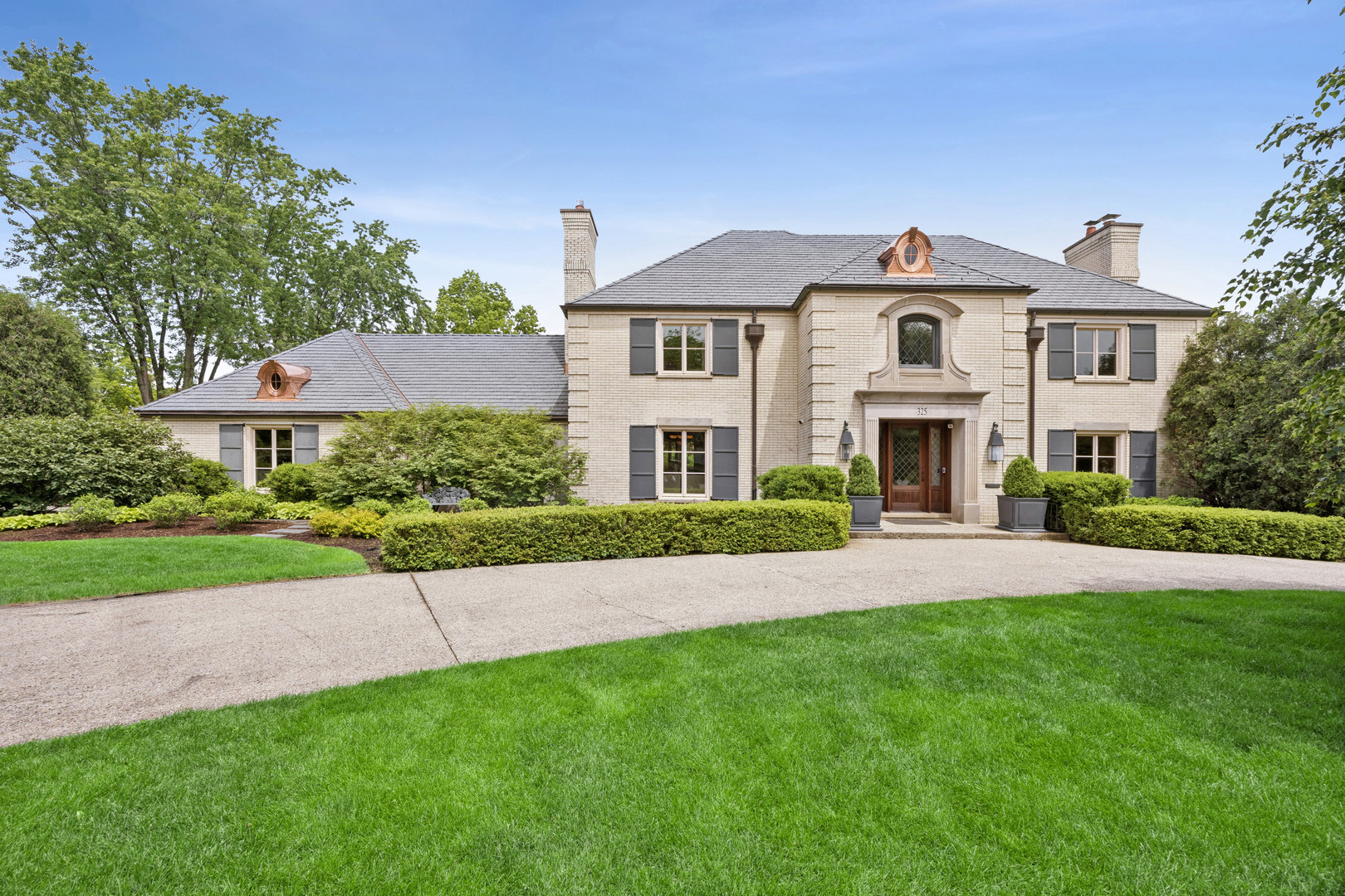 Originally built in 1979 and fully renovated down to the studs in 2008, the home offers the character of an established Hinsdale address with the updated feel, function, and quality today's buyers expect. Set on a beautifully landscaped corner lot in one of Hinsdale's most sought-after neighborhoods, this exceptional 7-bedroom, 6.2-bath residence offers over 6,100 square feet of refined living space thoughtfully designed for both everyday comfort and grand-scale entertaining. Timeless architecture, a circular front drive, and a brand-new DaVinci composite slate roof create an unforgettable first impression, while expansive interiors blend classic craftsmanship with sophisticated modern updates throughout.    A dramatic foyer with hardwood flooring, custom tile inlay, and an elegant elliptical staircase welcomes you inside. Gracious formal living and dining spaces feature extensive millwork, French doors, built-ins, and oversized windows that flood the home with natural light. The expansive family room is anchored by a fireplace and stunning beamed ceiling, seamlessly connecting to the chef's kitchen and outdoor entertaining areas. Designed for culinary enthusiasts, the kitchen showcases dual SubZero refrigerators, double Wolf ovens, Wolf cooktop, multiple prep areas, farmhouse sink, Miele dishwashers, oversized island seating, and an inviting breakfast area with beverage station and lounge space.    One of the home's most unique features is the beautifully appointed library/lounge wing with vaulted ceilings, fireplace, custom built-ins, marble surfaces, and direct access to the bluestone patios and backyard retreat. Multiple sets of French doors throughout the main level create effortless indoor-outdoor living.    The second level offers a luxurious primary suite complete with tray ceiling, dual walk-in closets, spa-inspired bath with steam shower, body sprays, and private water closet. Additional bedrooms are generously sized with beautifully updated baths and custom details throughout. The third floor provides incredible flexibility with two additional bedrooms, full bath, and bonus space ideal for guests, offices, or playrooms.    The finished lower level is designed for entertaining and recreation with a large rec room, dedicated home theater, fitness area, additional bedroom, and full bath. Outside, resort-style amenities include multiple bluestone patios, built-in firepit, hot tub with water feature, professionally landscaped grounds, and both attached and detached garages offering four-car capacity.    Additional highlights include whole-house audio, intercom system, ADT security, irrigation system, generator, zoned HVAC, hardwood floors throughout much of the home, and extensive recent improvements completed during a comprehensive renovation. A rare opportunity to own an extraordinary Hinsdale residence offering timeless elegance, exceptional functionality, and luxury living at every turn.