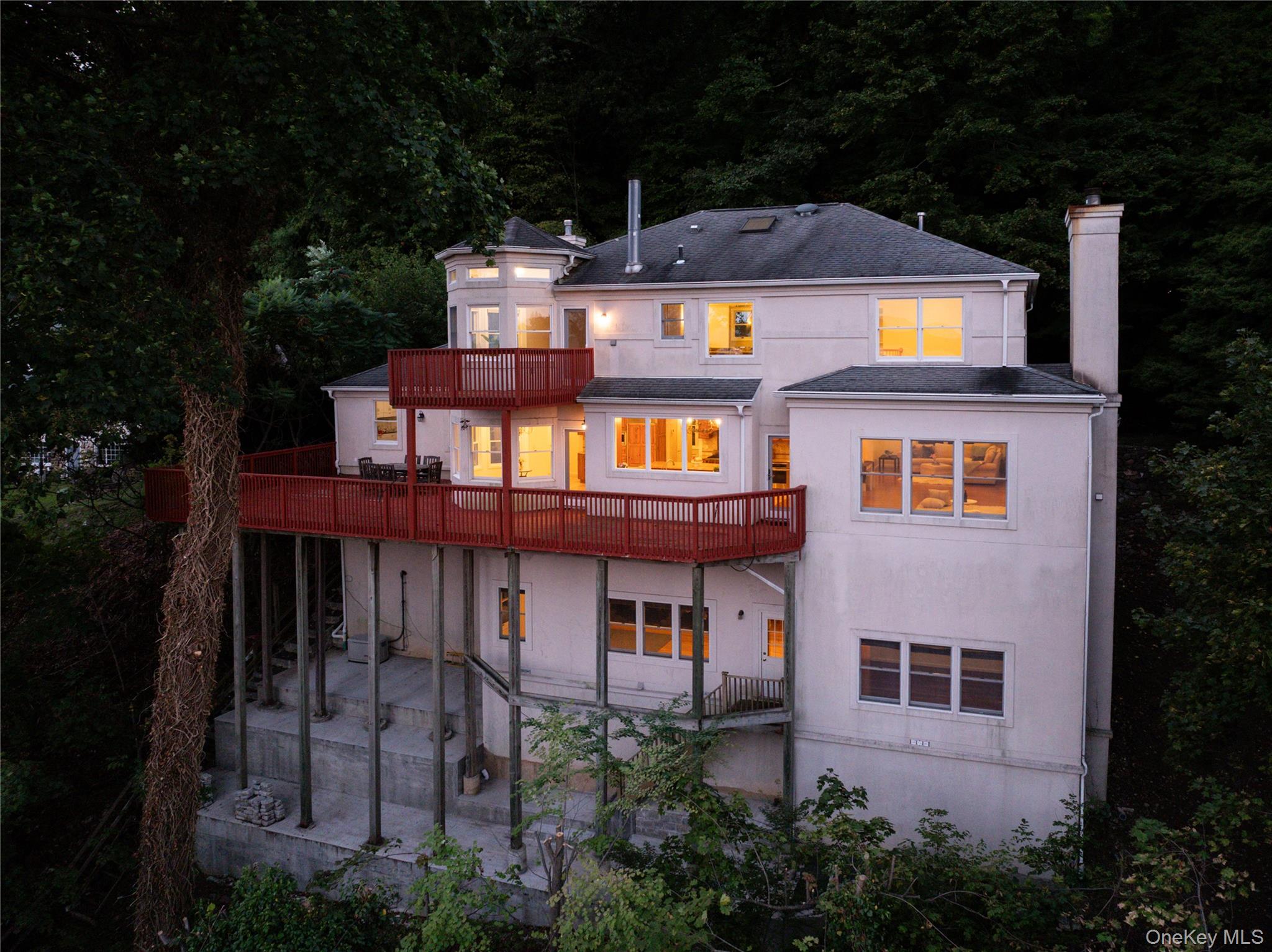 This 3888 square foot contemporary colonial offers stunning east facing views of the Hudson River all year round. This spacious 4-bedroom, 3.5-bathroom home features high ceilings, hardwood floors and an abundance of natural light throughout three levels of living. A welcoming entryway of custom wood and amber onyx opens up to a flowing open floorplan with large spaces, a woodburning fireplace and plenty of windows. 
The gourmet kitchen has newer high-end appliances, a range and an oven, a pot filler faucet, an oversized kitchen island and two doors out to the deck which spans nearly the width of the house with a propane line for your grill.
The primary suite boasts an en suite bath with double sinks set into a luxurious jade vanity top and gas fireplace. You are sure to enjoy quiet sunrises and beautiful summer evenings on the private deck.
2 car garage with whole house generator and EV outlet. Driveway parking for 3+ cars and a cobblestone and wooden stairway leading to your own access to the Esposito trail.
Explore the hiking trails and scenic walkways, browse the unique local shops, and savor the farmers markets, street fairs and festivals throughout the Hudson Valley. Nyack is just 16 miles from the George Washington bridge and has access to trains and buses into NYC.