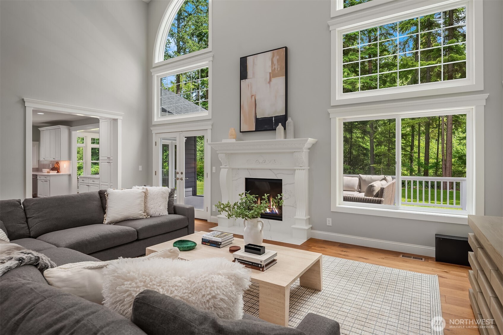 Walls of windows and soaring ceilings fill the great room with natural light, creating an inviting gathering space overlooking the private backyard.
