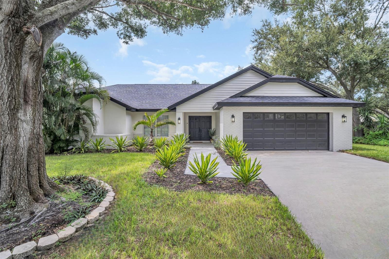 Gorgeously renovated and perfectly situated between Palm Harbor and Dunedin, this stunning 4-bedroom, 3-bathroom home in the sought-after Waterford Crossing community offers luxury living at its finest. Step through the elegant double-door entry and be welcomed by soaring vaulted ceilings, a freshly painted interior, all updated fans, fixtures, and hardware, and beautiful sea salt luxury vinyl flooring that flows seamlessly throughout the thoughtfully designed open and split-bedroom floor plan. The heart of the home is an absolutely jaw-dropping kitchen renovation, featuring quartz countertops, custom backsplash, an oversized island plus a breakfast bar, all brand new LG appliances, and modern recessed lighting—opening beautifully to the spacious family room with a wood-burning fireplace and custom built-in desk. The primary suite is a true oasis with large sliders leading out to the screened lanai and peaceful conservation views of the over half-acre lot and showcases a spacious walk-in closet plus a separate built-in, a luxurious en-suite bath complete with dual vanities, a dedicated make-up station, a brand-new deep soaker tub, and a stunning walk-in glass shower with custom tile and rain showerhead. The freshly screened lanai features two sets of large sliders and two double doors from the main living areas, creating an ideal indoor-outdoor flow for relaxing or entertaining. This home is truly move-in ready with a freshly painted exterior, sleek new exterior lighting, and major upgrades including a brand NEW ROOF (2024), HVAC (2024), electrical panel (2024), and hot water heater. Located in a NON-FLOOD ZONE, but just a short walk or jog to the Dunedin Causeway, Honeymoon Island, Caladesi Island, and beautiful Gulf Beaches. Waterford Crossing offers a beautiful community park, scenic trails and nearby with easy access to the Pinellas Trail. With a recently passed 4-point inspection and essentially EVERYTHING NEW, there are no insurance worries. Zoned for top-rated schools and close to vibrant dining, shopping, and entertainment, this home offers better-than-new construction in an unbeatable location—an exceptional opportunity you don’t want to miss!