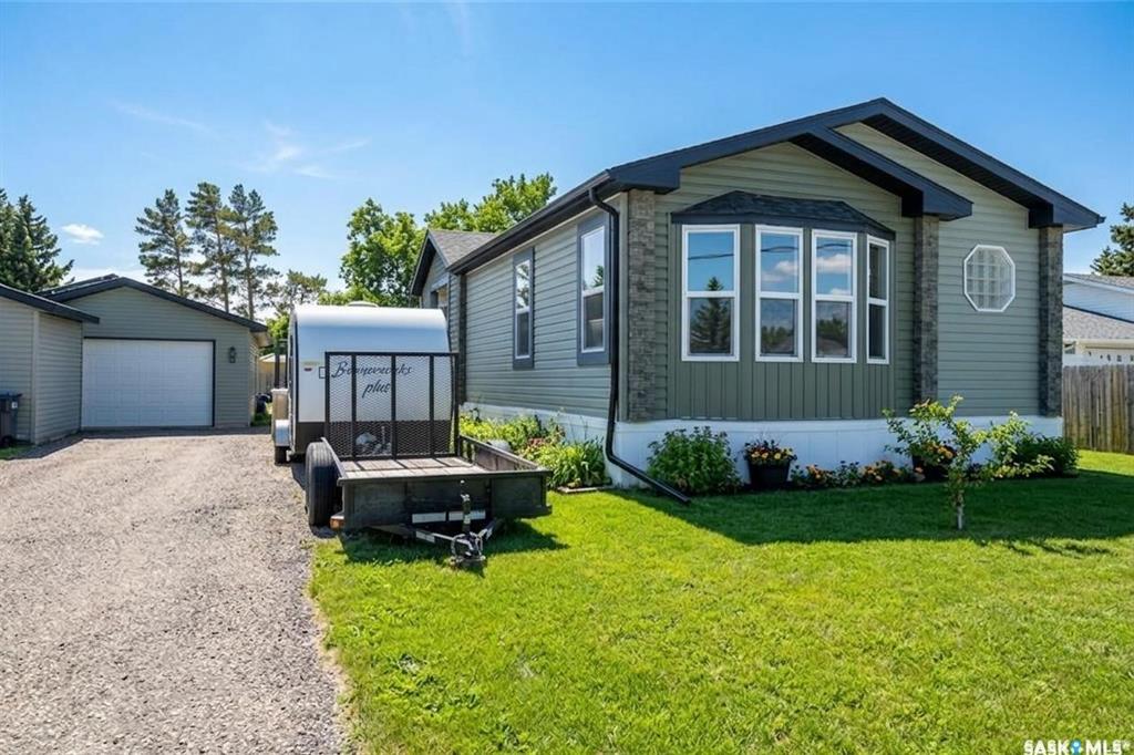 Welcome to 229 Poplar Street in the charming community of Wolseley, Saskatchewan — The Town Around a Lake — where history, natural beauty, and small-town warmth come together. This original owner, exceptionally well-maintained 2013 manufactured home, has an impressive 1,694 sq ft of thoughtfully designed living space. Vaulted ceilings and an open-concept layout create a bright, airy feel throughout the main living areas. The modern kitchen features a large island, abundant cabinetry, and seamless flow into the dining and living rooms, perfect for entertaining or everyday family life. The primary suite is privately positioned at the front of the home and includes a full 4-piece ensuite. Toward the back, you’ll find a spacious family room, two additional generously sized bedrooms, & another full bathroom, an ideal setup for family members or guests. A second entry leads into a convenient mudroom/laundry area, a practical bonus for busy households.Step outside and enjoy everything this beautiful lot has to offer. The yard is fully fenced with raised garden beds and a separate open green space perfect for extra parking, kids at play, or hosting gatherings. A custom-built firepit area adds charm and creates the perfect setting for relaxing summer evenings. The exterior features maintenance-free siding and a large deck spanning the side of the home — ideal for outdoor entertaining. The impressive 20' x 28' insulated detached garage is heat-ready and equipped with a 220 plug and 30-amp breaker for trailer parking. Two storage sheds provide even more functional space. Additional upgrades include: Solar panels installed on the garage, that power the entire property (2019), Reverse osmosis water system, New water heater (2024), Newer Fridge,Stove,Dishwasher,Washer, Triple pane windows in living room & family room, Home secured on 18 screw piles. This one-owner home truly shows pride of ownership, move-in ready. Schedule your showing today — you won’t want to miss this one!