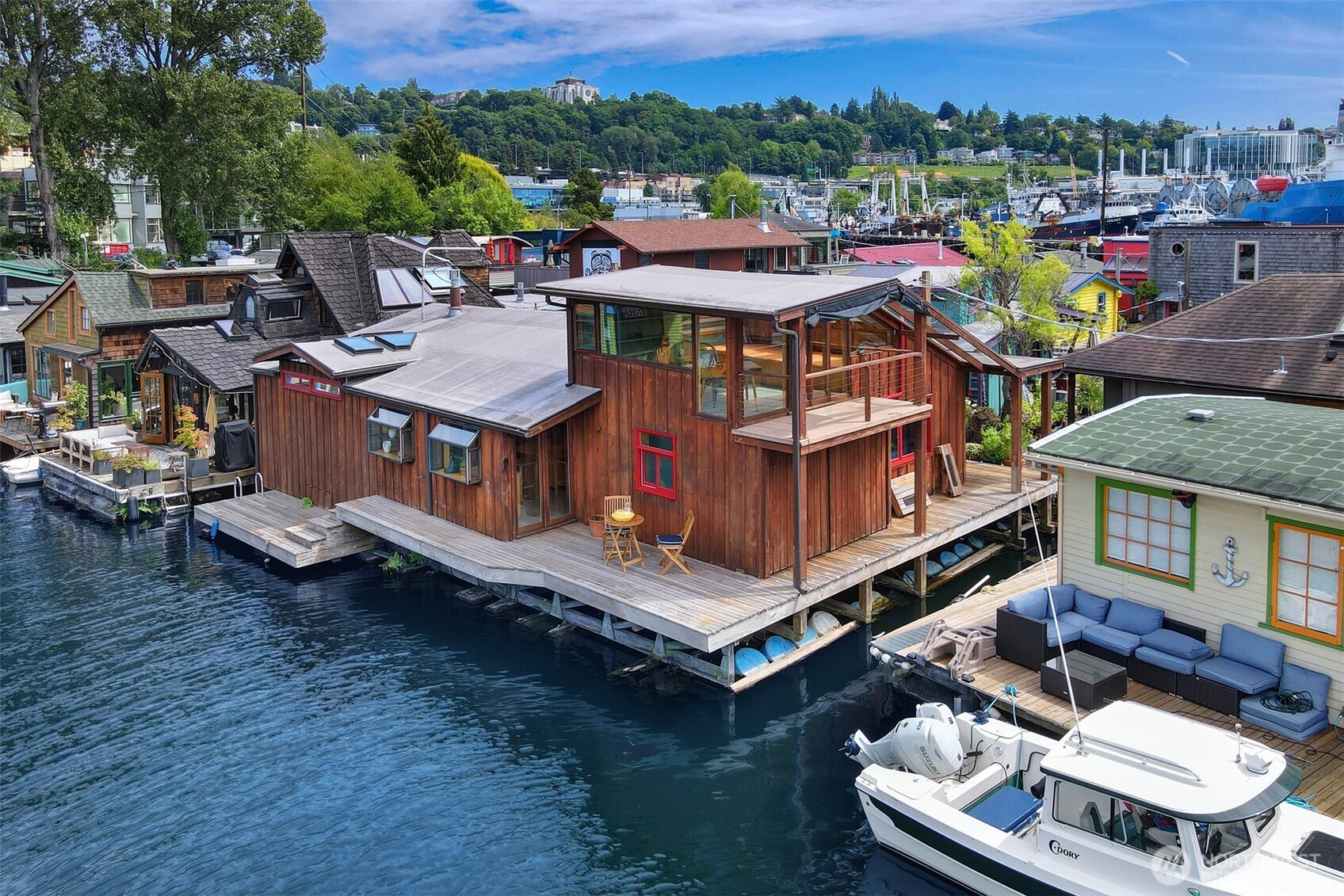 Three decades ago, a couple were ready to downsize from a land home. The vibrant views, sense of community, and the way of floating life appealed to them. They've been here ever since. But now the time has come to pass the opportunity on to the next lucky duck. The natural gas fireplace and cooking range is a perk living on a floating home.  So is the feeling this home gives as soon as you step aboard.  A massive covered front porch with beautiful flower pots welcomes you home. Original hardwood floors, built ins, and one of the best reading nooks we've seen. Perched above your neighbors, this enclosed room is one to linger for hours. The cedar plank exterior outside gives way to a very vibrant two bed + den, one bath home and lots of love.