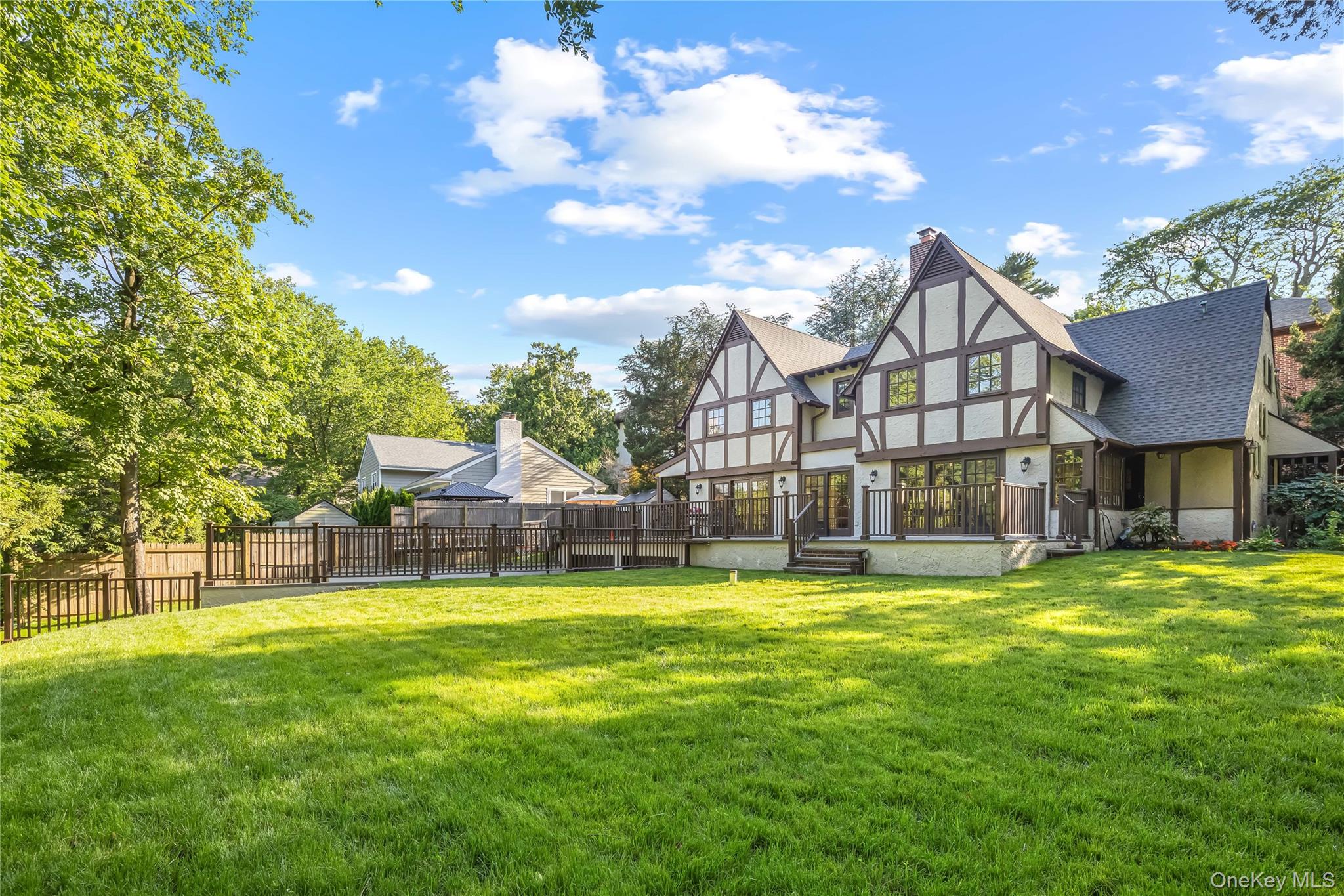 Welcome to this stunning, newly renovated Tudor-style residence in the heart of Douglaston. A park-like setting surrounds this elegant, immaculate Tudor, offering timeless charm, generous living space, and exceptional indoor-outdoor living on an expansive 110 × 110 lot. This impressive 5-bedroom, 3.5-bath home features approximately 2,800 square feet of thoughtfully designed living space, perfect for both everyday living and entertaining. The main level showcases sun-filled interiors, rich hardwood floors throughout, a spacious formal living room with fireplace, and an inviting family room with multiple French doors that open to a large elevated deck overlooking the private backyard. The updated chef’s kitchen features custom wood cabinetry, stone countertops, and premium Viking appliances, complemented by a bright breakfast nook and easy access to the outdoor entertaining area. A formal dining room provides the perfect setting for gatherings and holiday meals. The second level offers four well-proportioned bedrooms, including a primary suite with 2 walk-in closets and private bath, along with additional bathrooms to comfortably accommodate guests.The finished lower level provides excellent bonus space with a recreation room, utility area, and additional flexible rooms ideal for a home office, gym, or playroom. Additional highlights include a two-car garage and long private driveway, providing convenience and ample parking. Set on beautifully landscaped grounds, the property features a large deck, patio area, and spacious backyard, perfect for outdoor entertaining or quiet relaxation. Located in one of Queens’ most desirable neighborhoods, this home offers convenient access to top-rated schools, parks, shopping, dining, and transportation, while maintaining the peaceful charm of Douglaston living.A rare opportunity to own a distinctive and spacious home in a premier location. Must See.