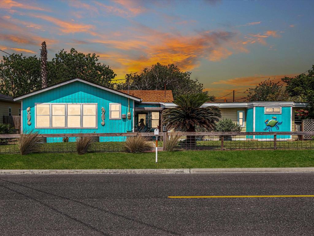 Vibrant blue house with palm trees and crab mural, showcasing coastal charm in Rockport, Texas, ideal for potential homebuyers exploring property listings.